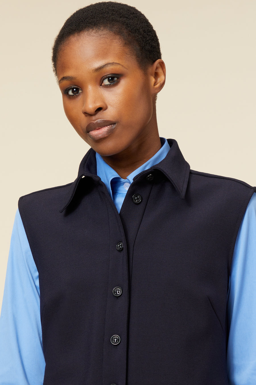 Navy wool-blend waistcoat with classic black buttons over a light blue shirt, creating a sophisticated layered look.