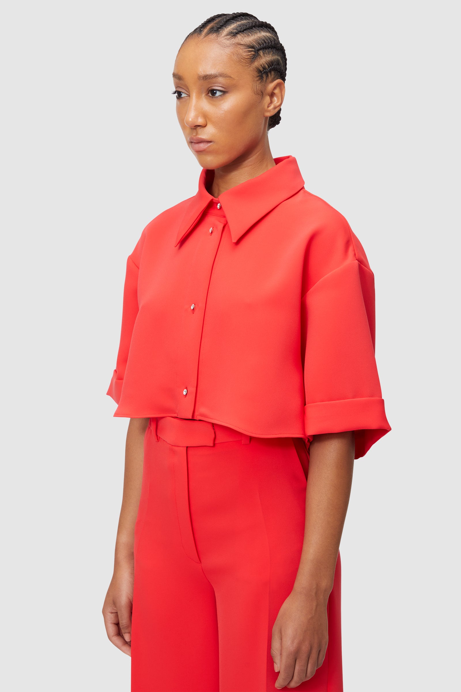 Red tailored shirt and pants ensemble featuring crisp detailing and structured design for a bold fashion statement.