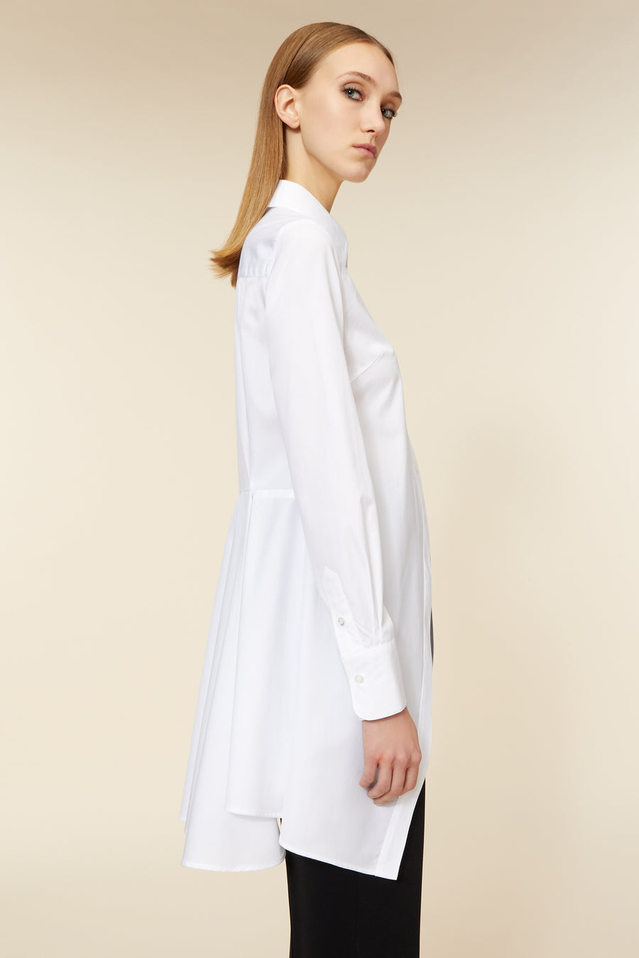 A white longline shirt with classic collar and buttoned cuffs, expertly tailored for a sleek, minimalist silhouette.