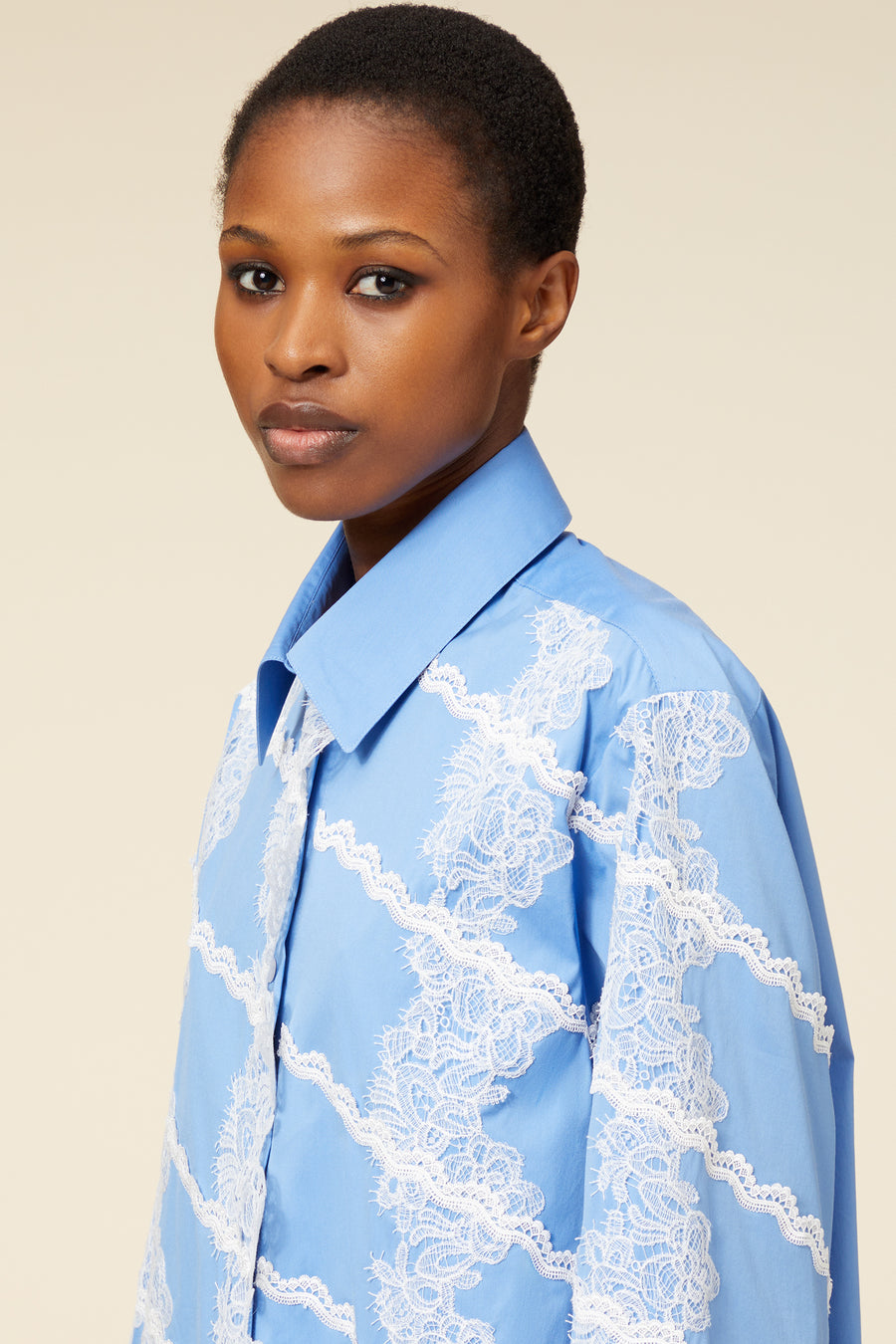 Close-up of a blue blouse adorned with intricate white lace embroidery, featuring a classic collar and elegant design.