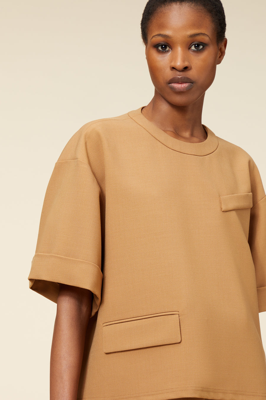 Loose-fit tan cotton top with oversized short sleeves and front patch pocket, featuring clean lines and minimal design.