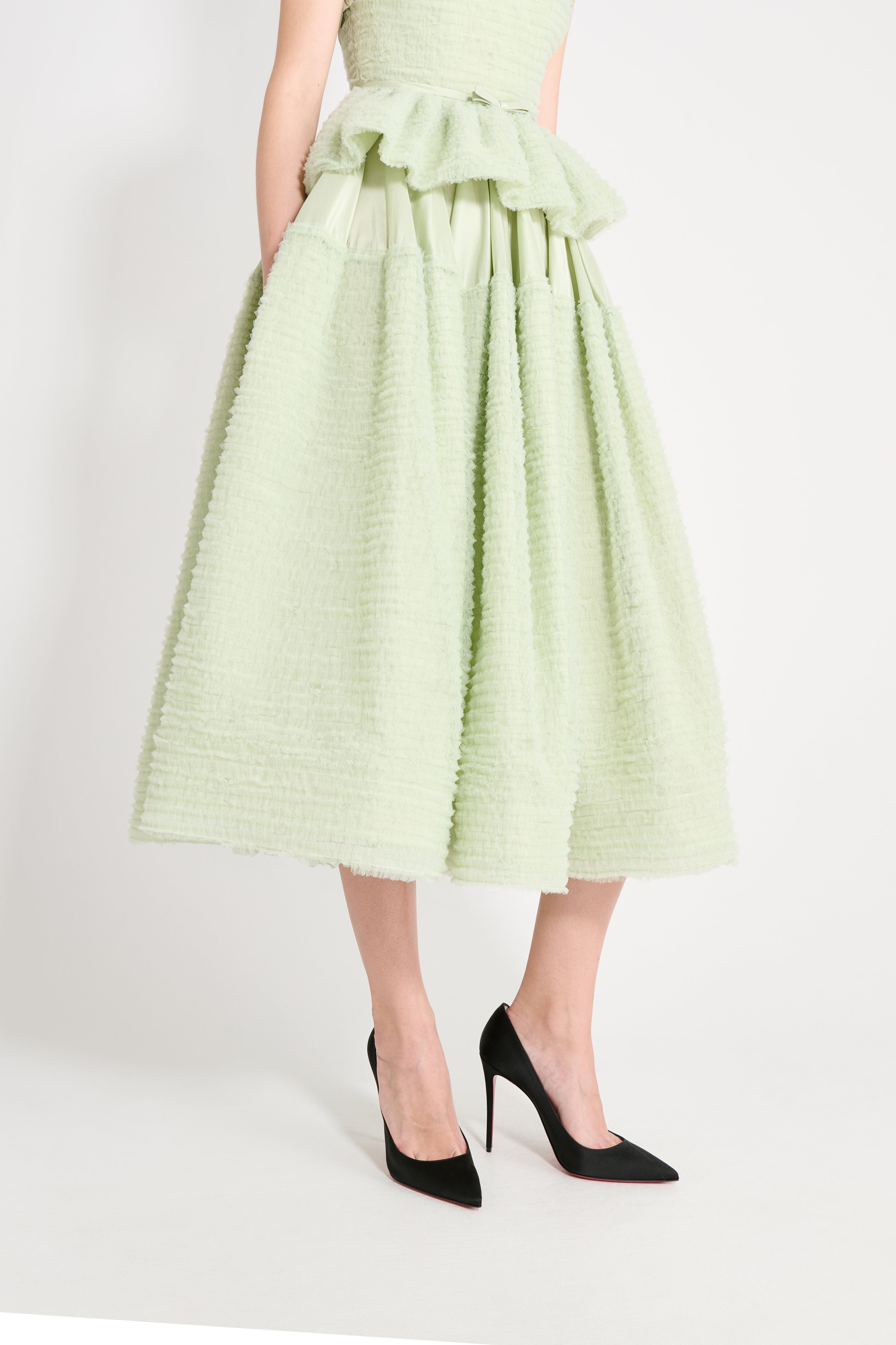 Light green dress with ruffled details worn by a person on a white background