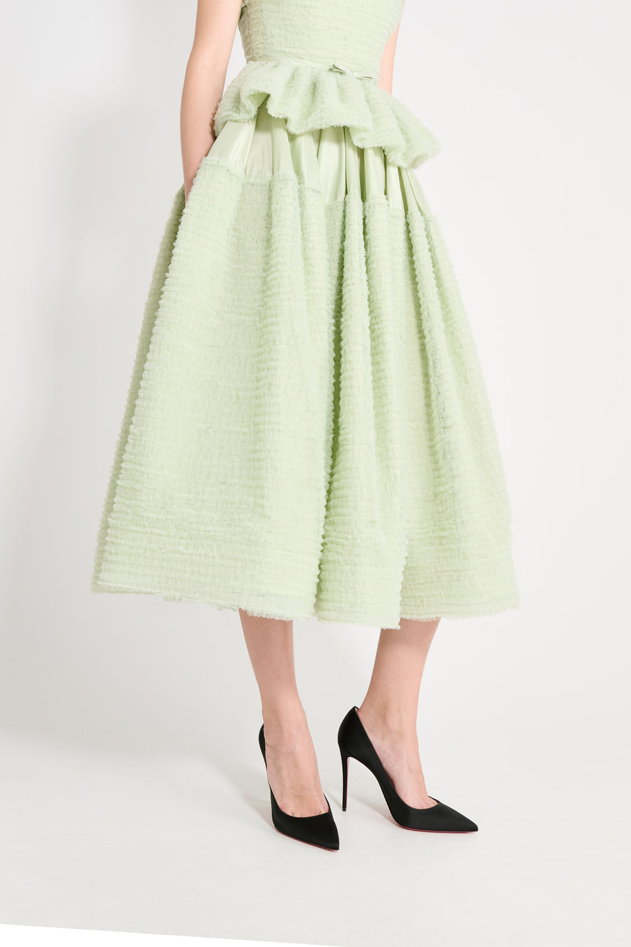 Light green dress with ruffled details worn by a person on a white background