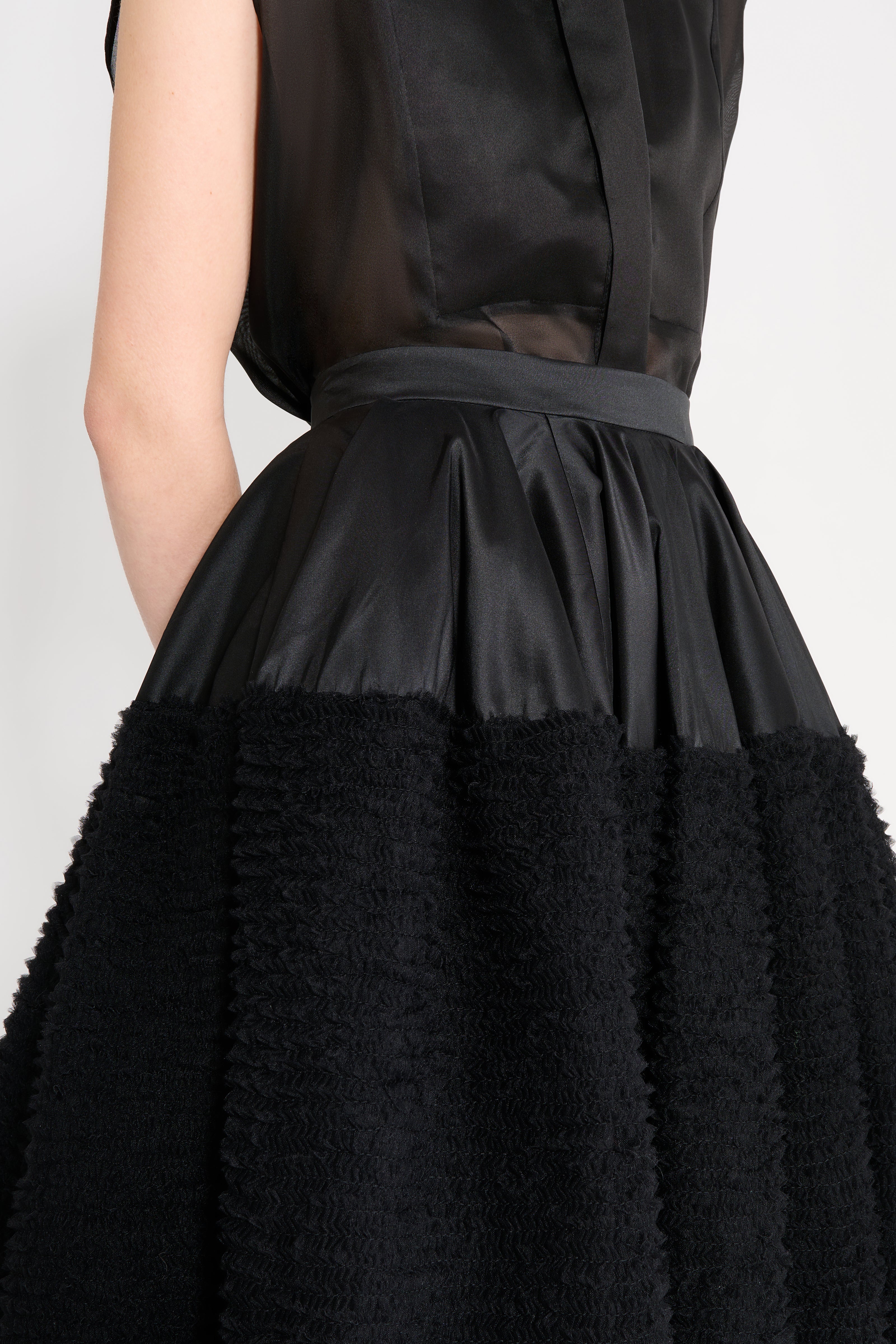 Black dress with textured skirt and sheer top on a white background
