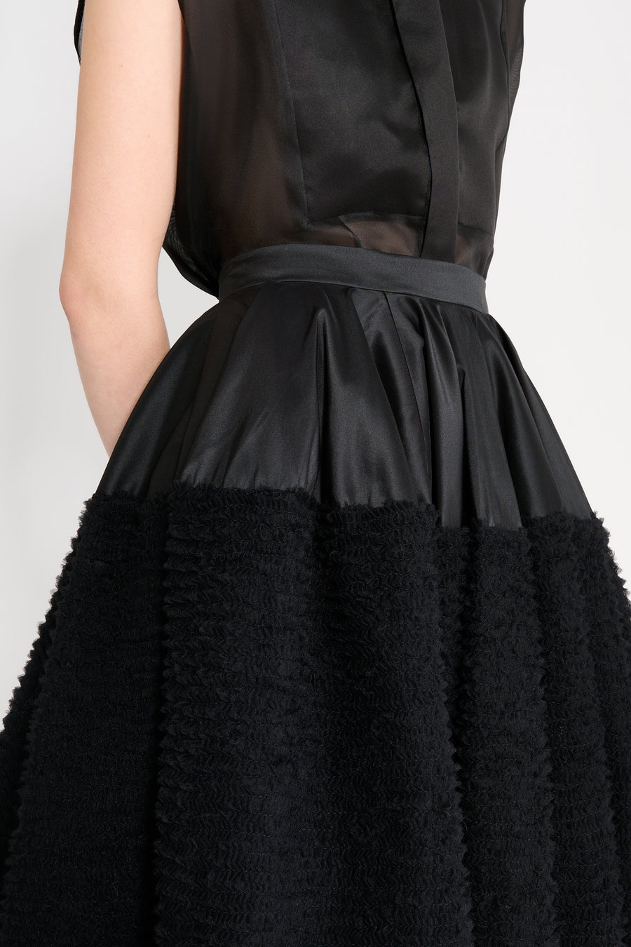 Black dress with textured skirt and sheer top on a white background