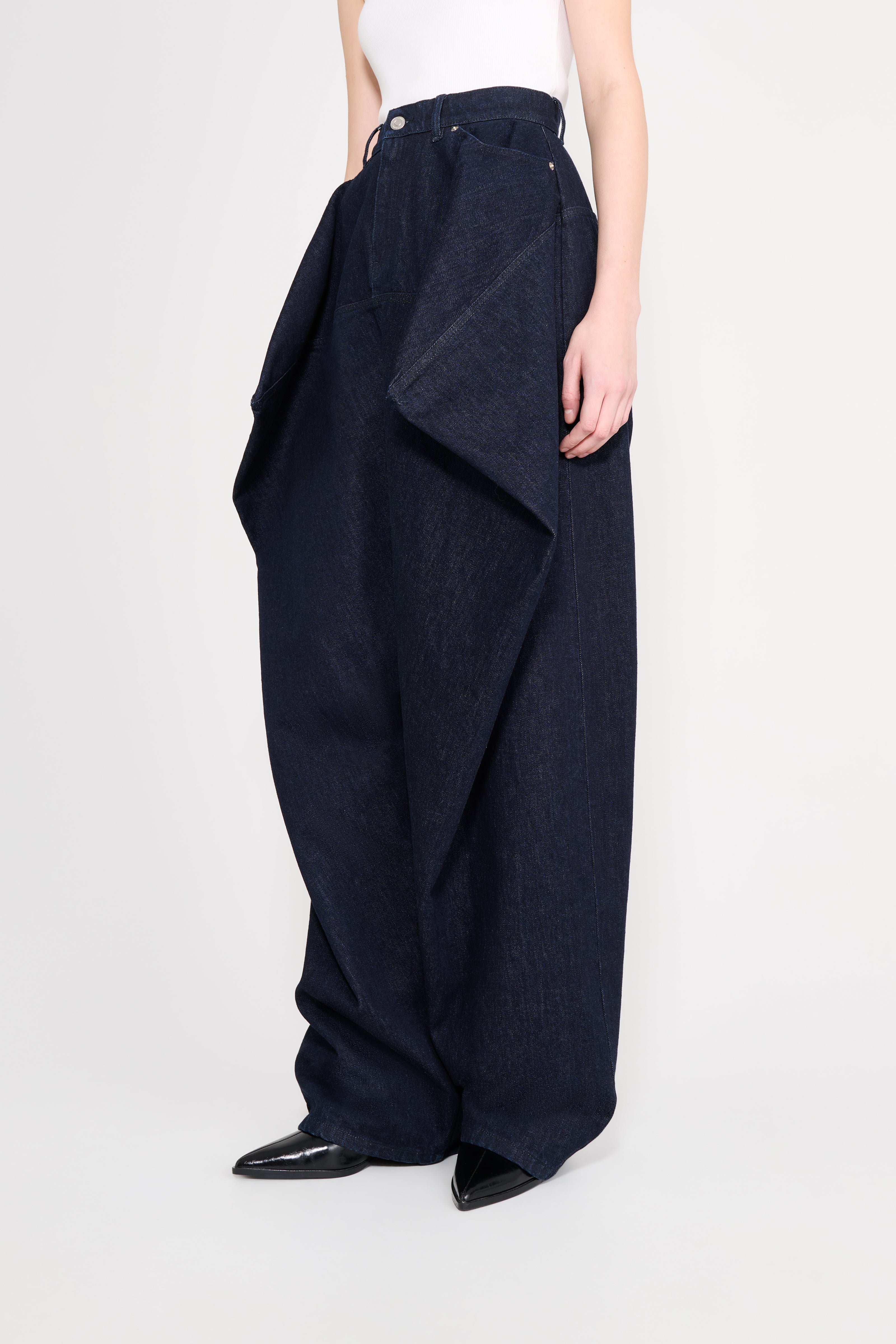 Person wearing a pair of dark blue wide-leg pants on a white background