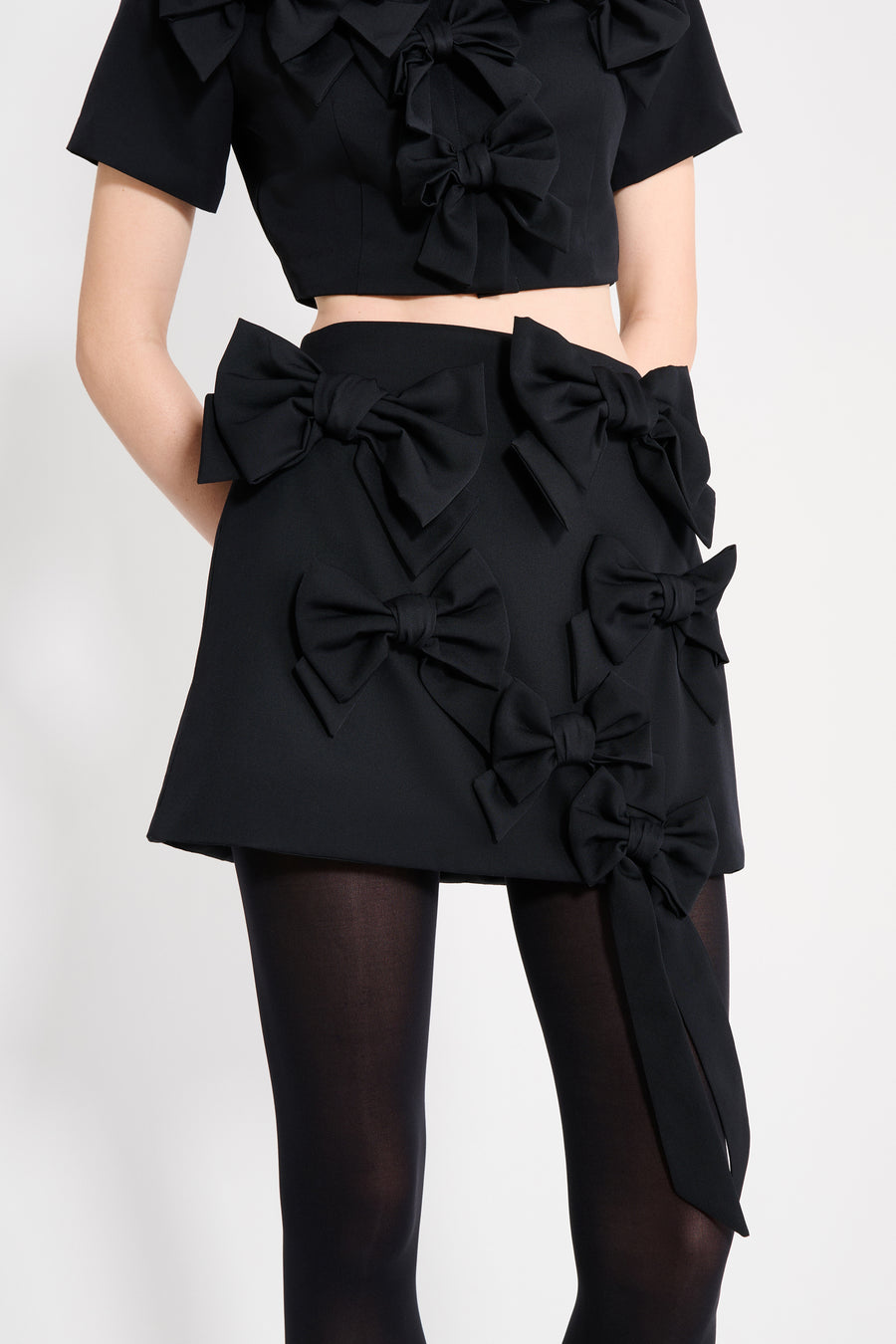 The wool skirt features the seasonal bow bouquet technique, where timeless elegance meets refined craftsmanship in a seamless fusion of sophistication and grace