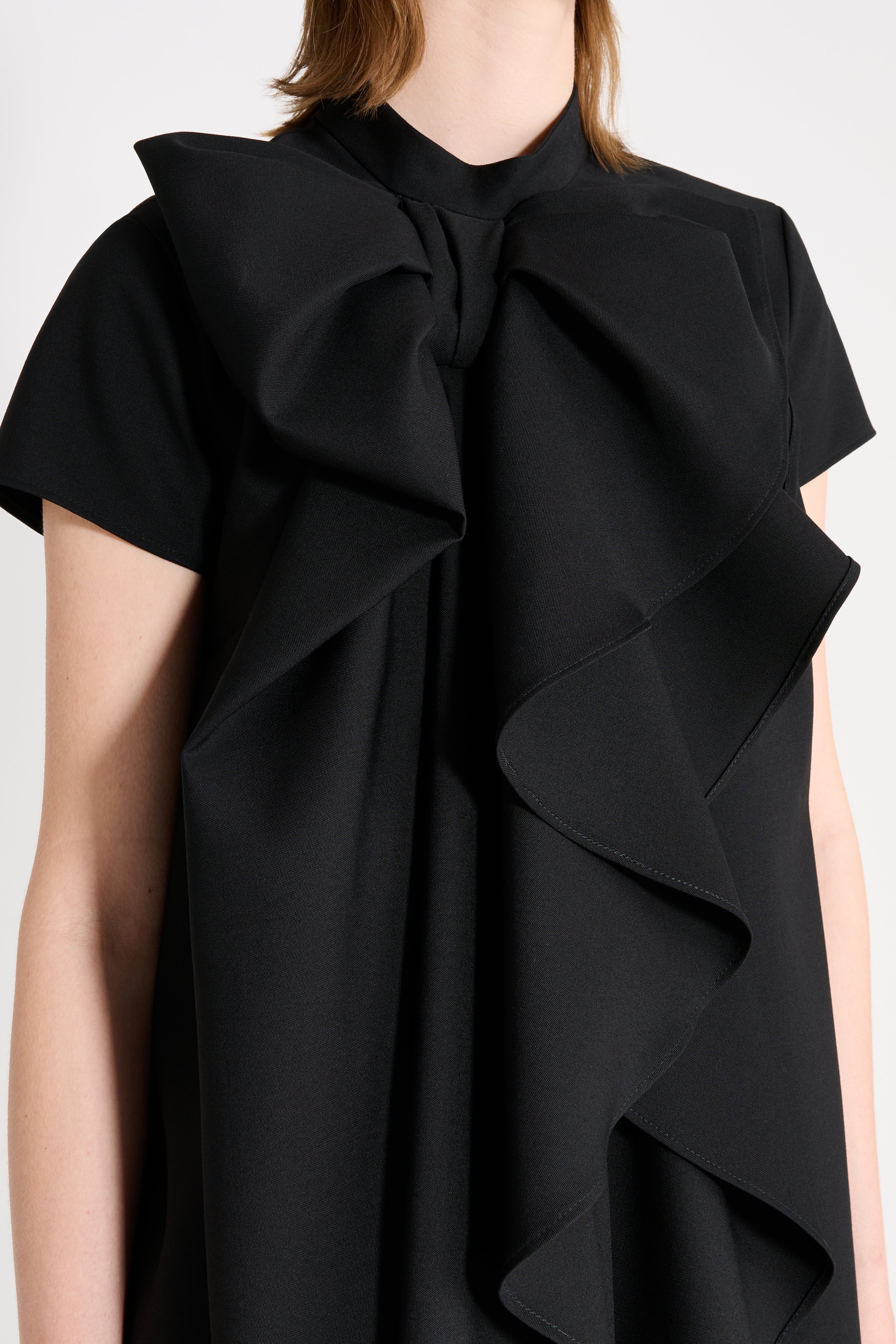 Close up on a model wearing a black dress.