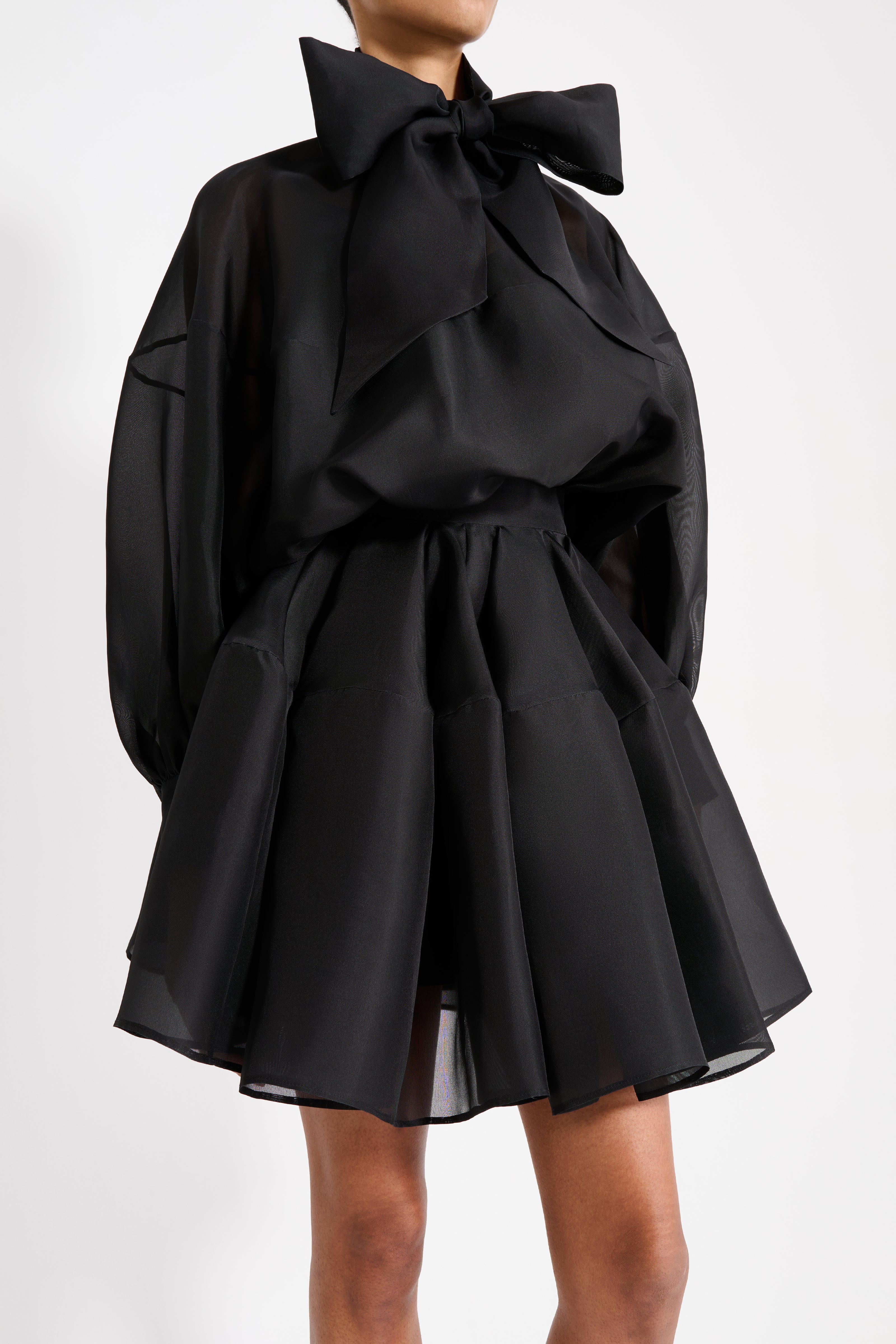 Black dress with a large bow detail on a white background