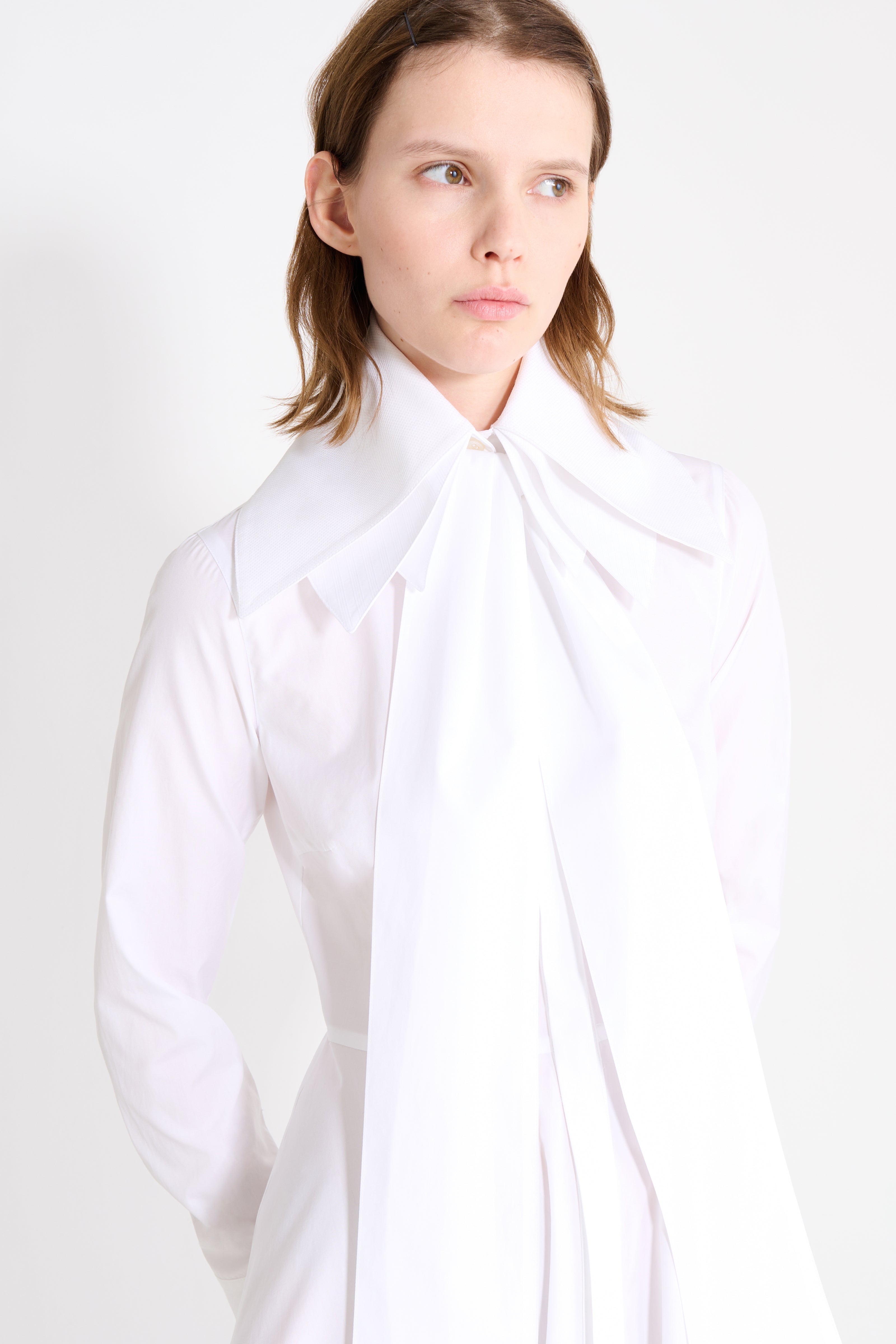 Person wearing a white shirt with a high collar against a white background