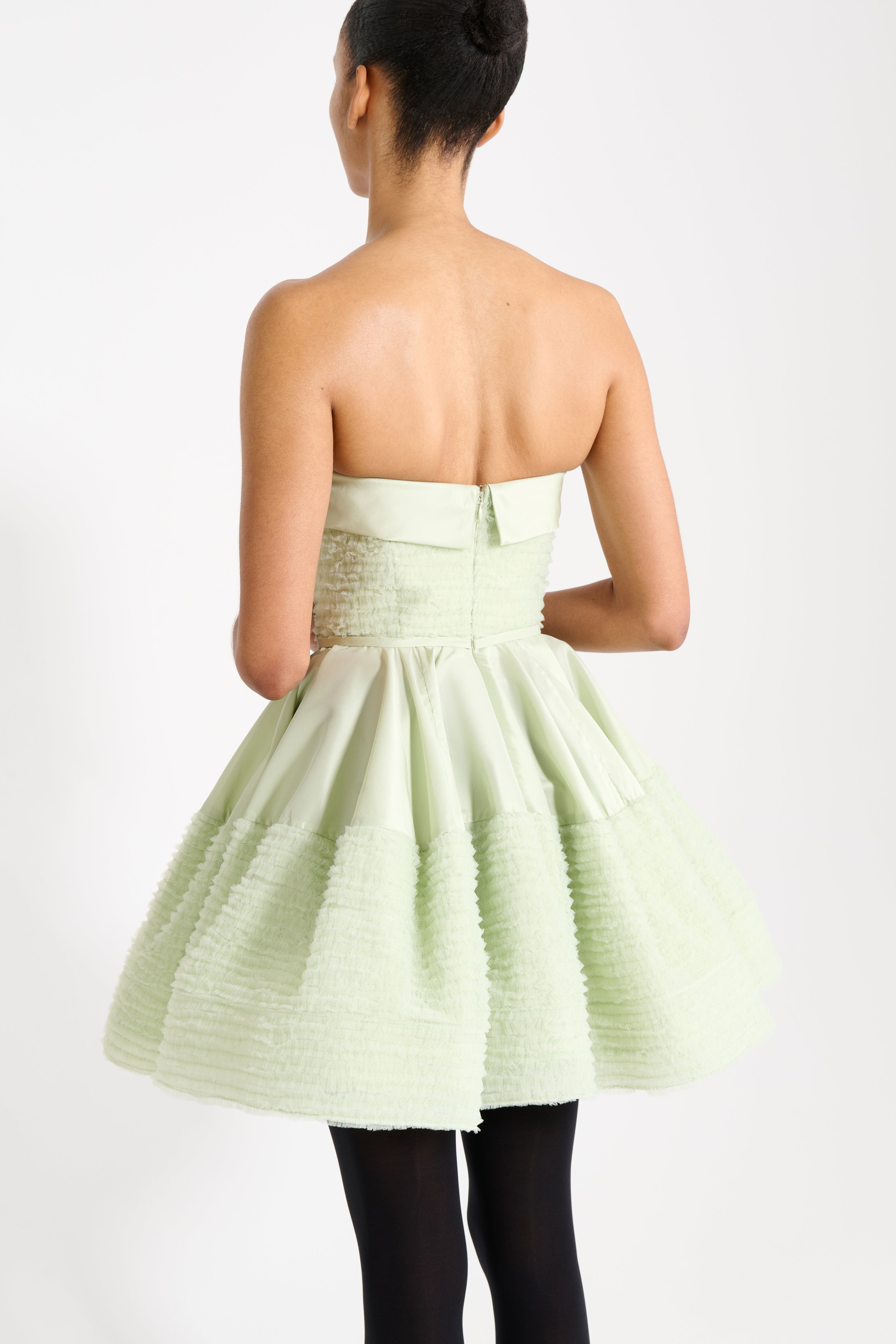 Woman wearing a light green strapless dress on a white background