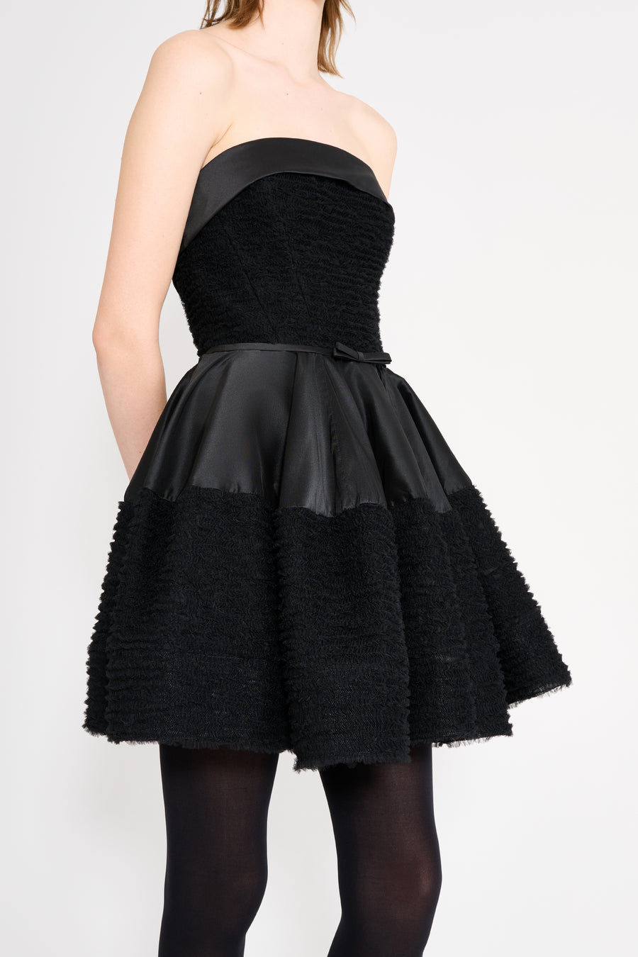 Black strapless dress with textured fabric on a white background