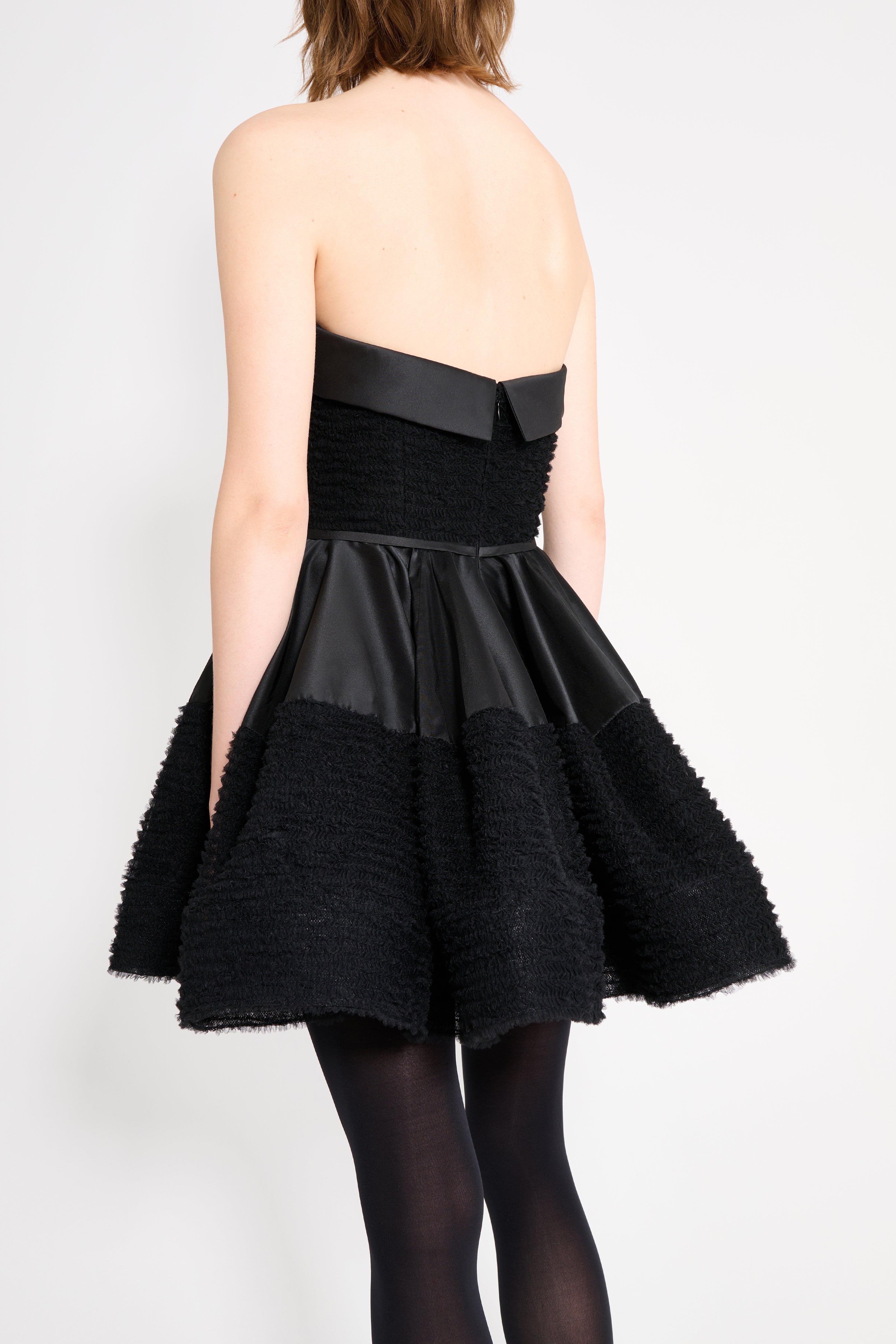 Black strapless dress with a textured skirt on a white background