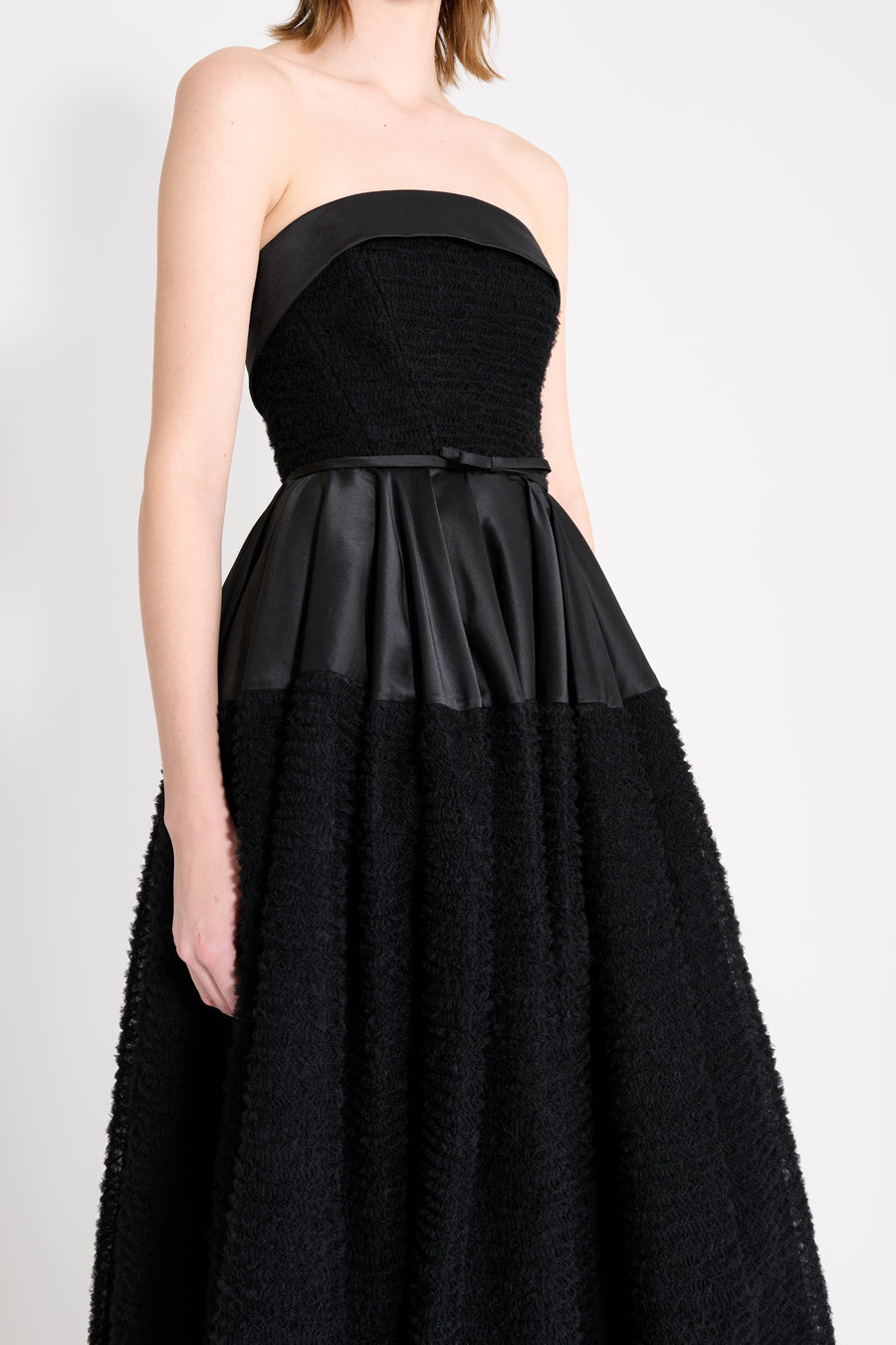 Close up on the model wearing a black strapless gown.