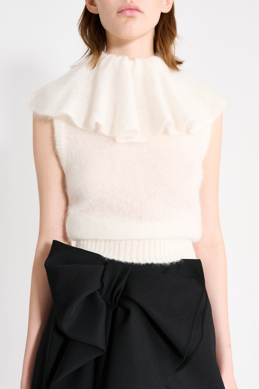 Close up on a model wearing a white volant neck top.