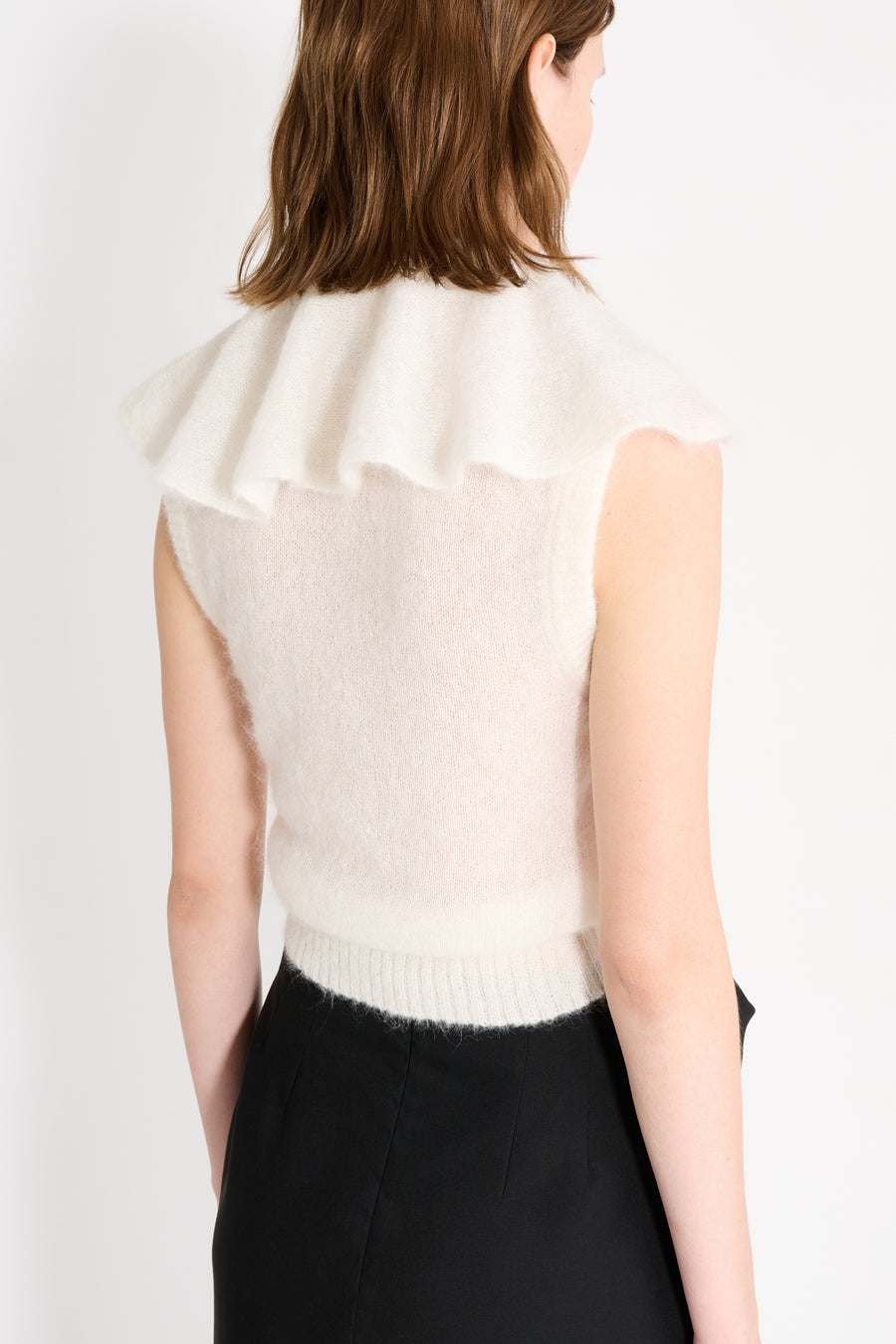 Close up on a model wearing a white volant neck top shown from the back.