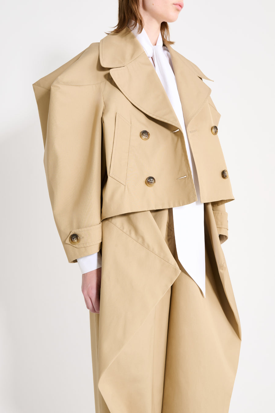 Beige trench coat with white shirt on a plain background