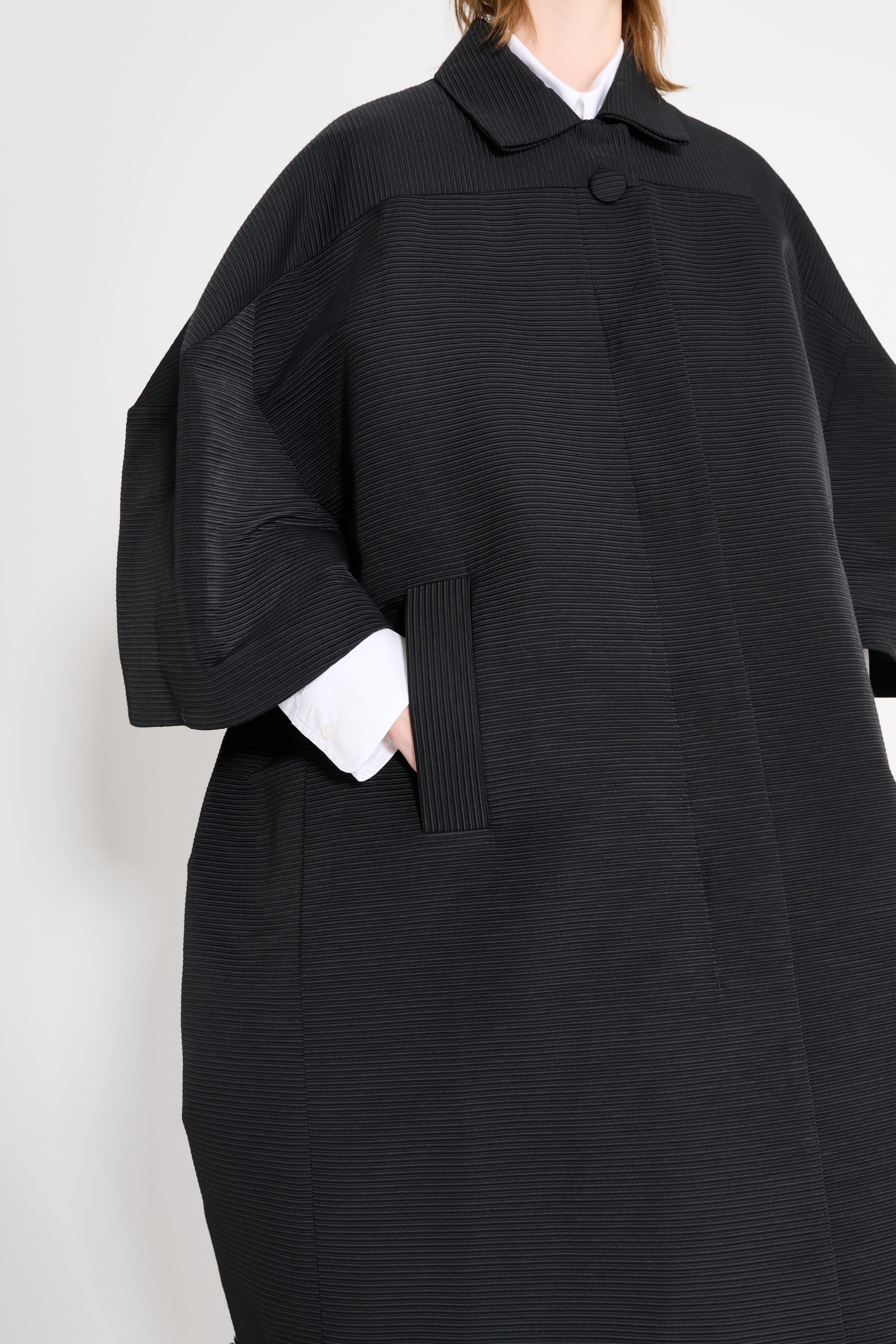 Black coat worn by a person on a white background