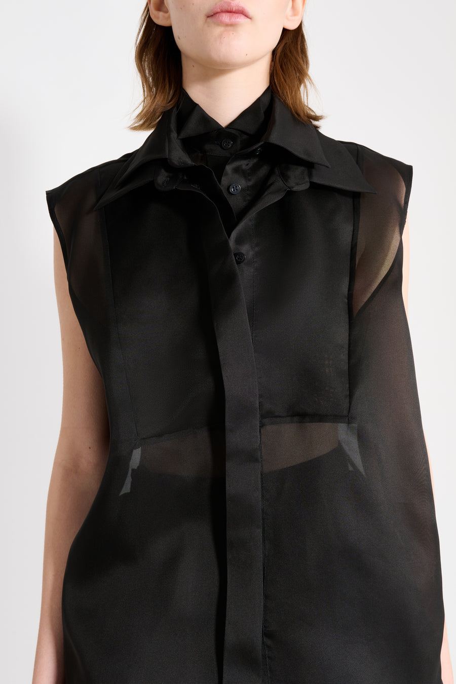 Black sleeveless garment with sheer overlay on a white background