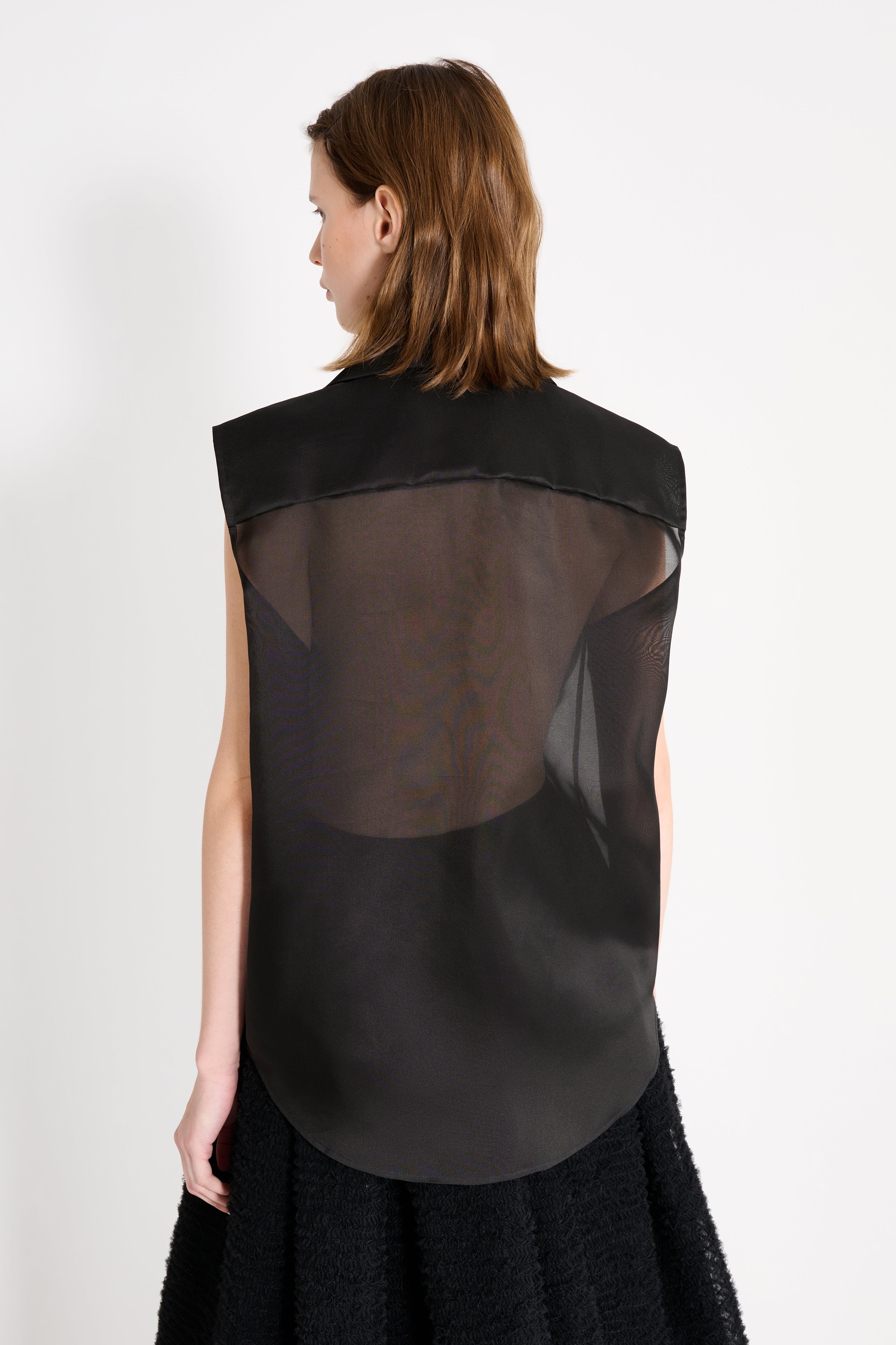 Black sleeveless top with sheer back on a white background