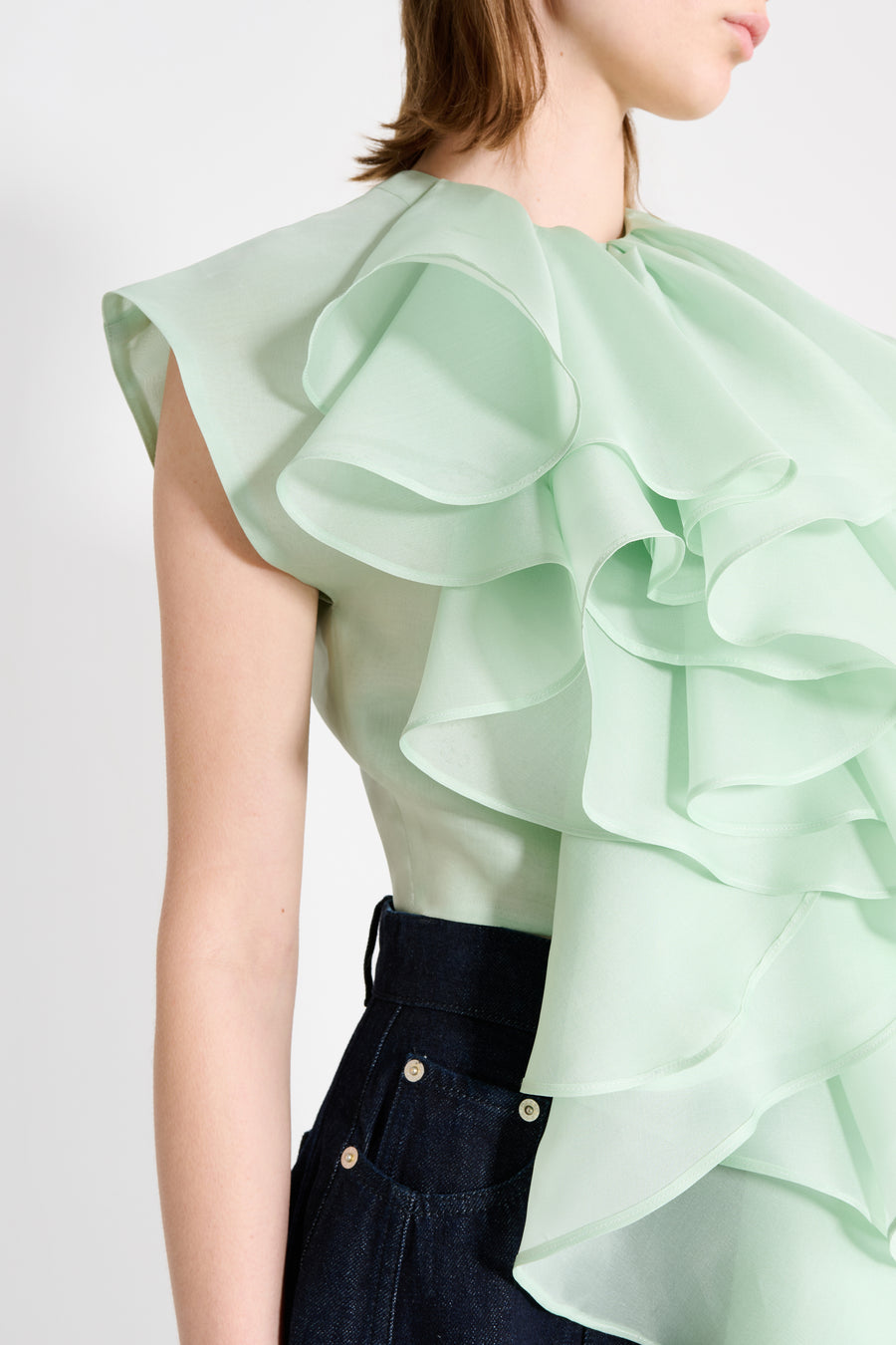 Light green ruffled blouse worn by a person on a white background