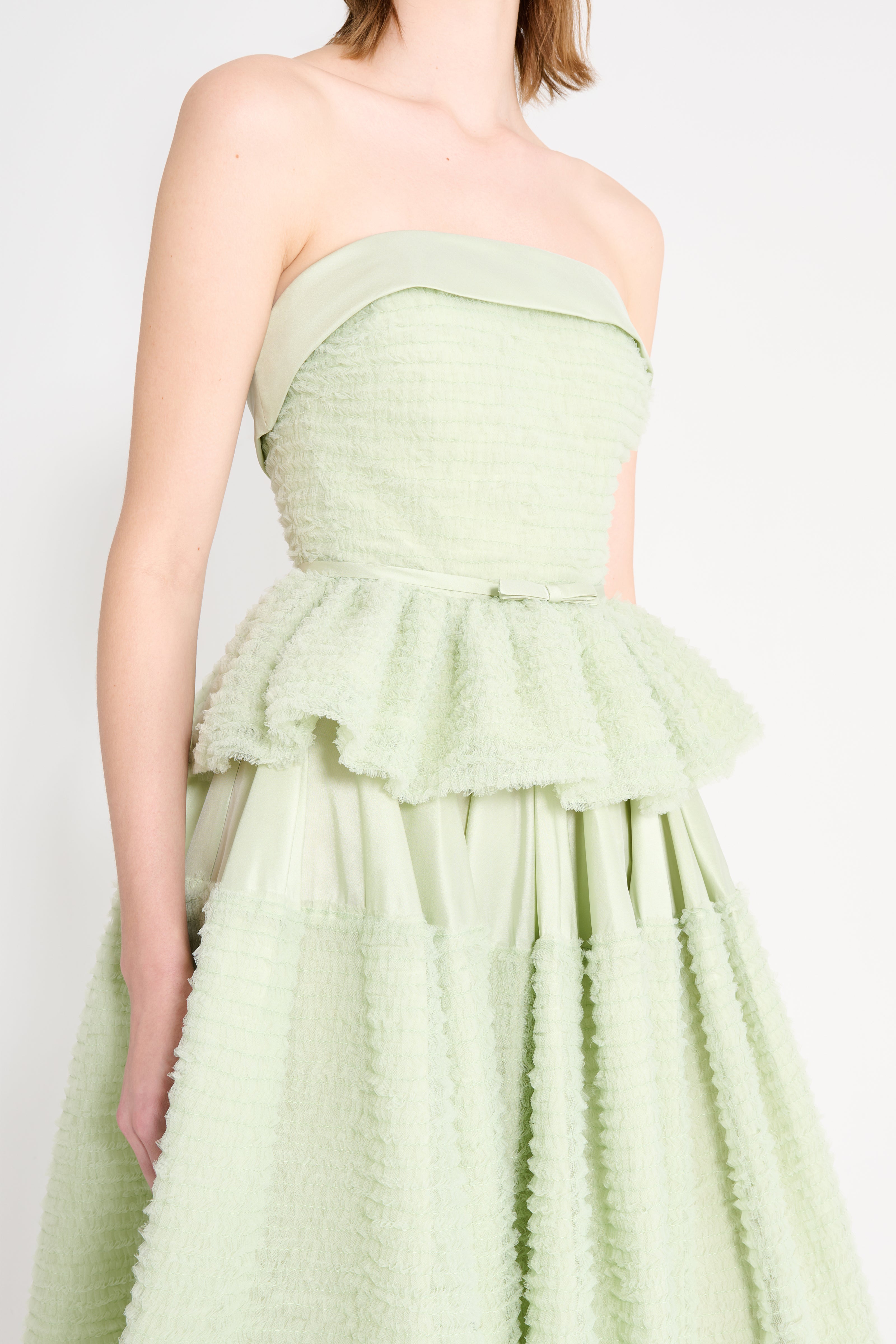 Light green strapless dress with ruffled layers on a white background