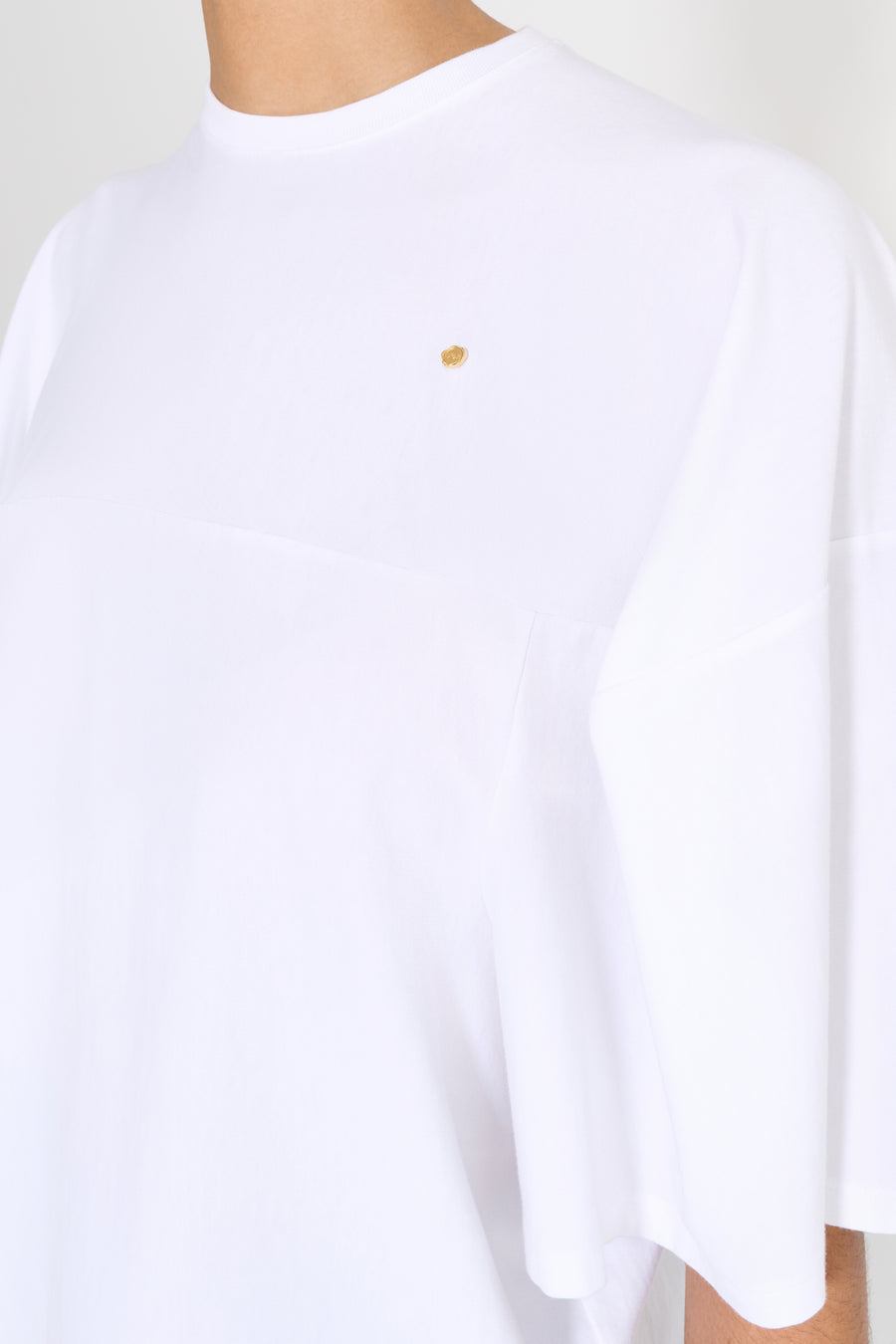 White t-shirt with a small yellow logo on a white background