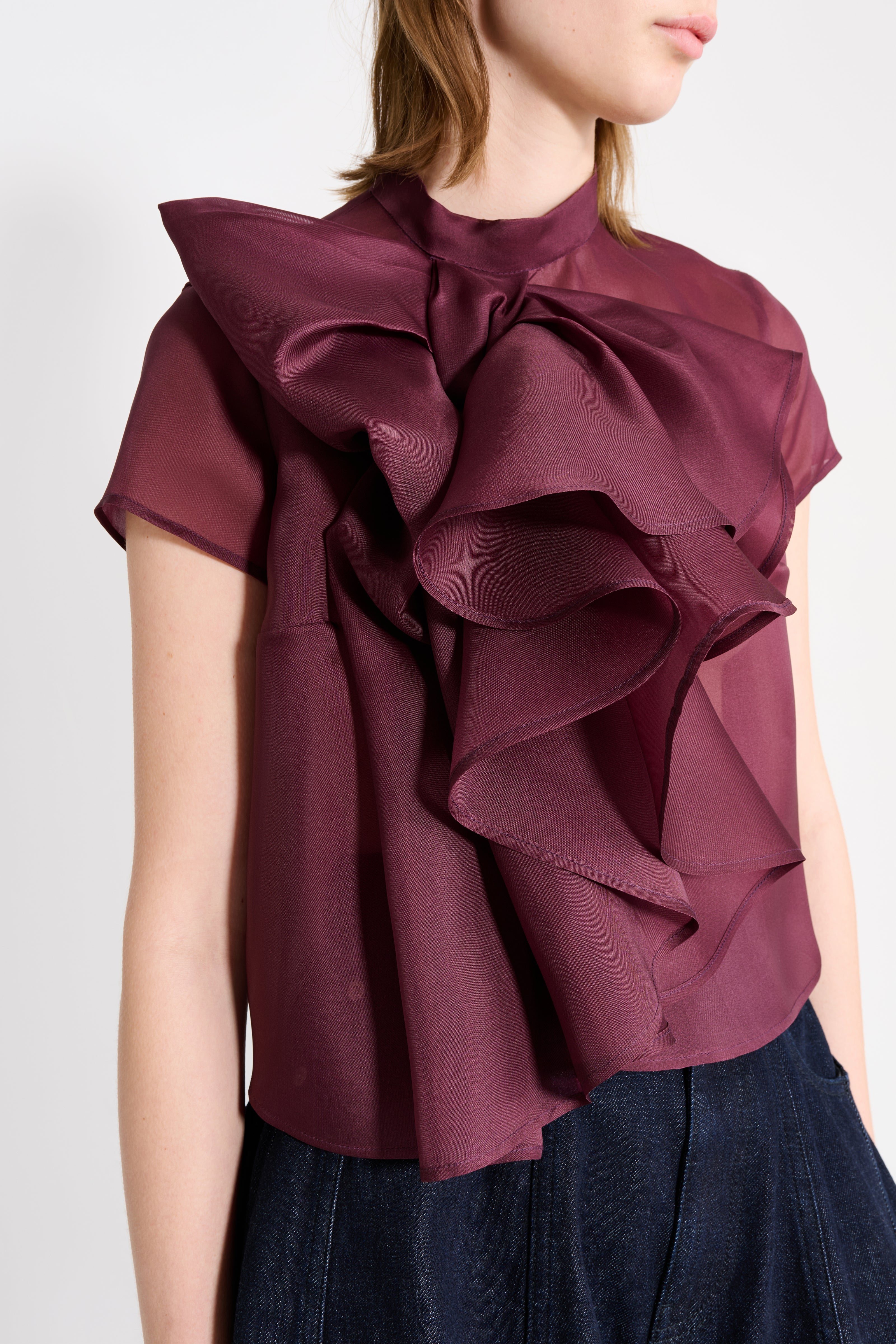 Maroon ruffled blouse worn by a person on a white background