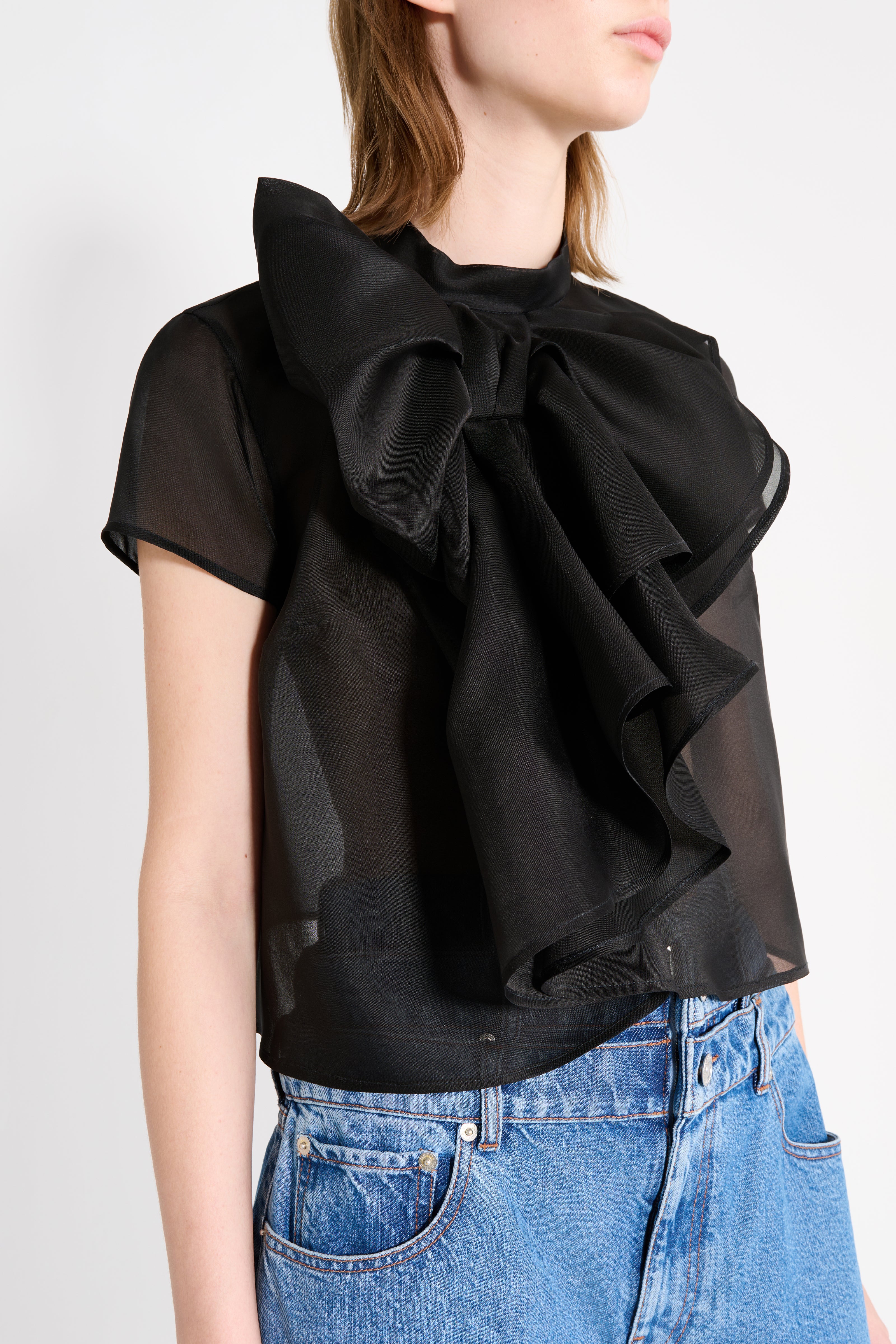 Black ruffled blouse worn by a person on a white background