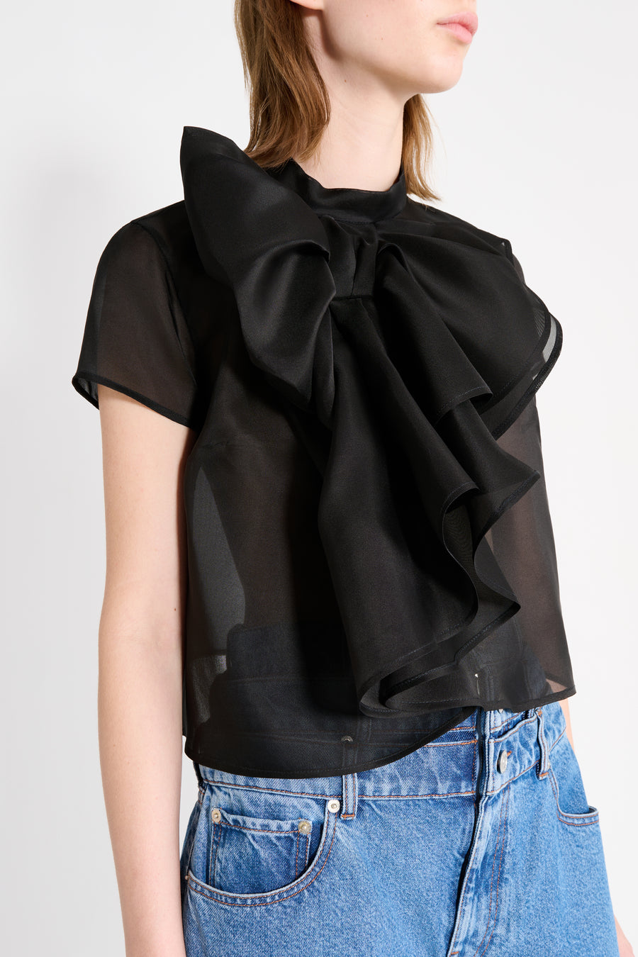 Black ruffled blouse worn by a person on a white background