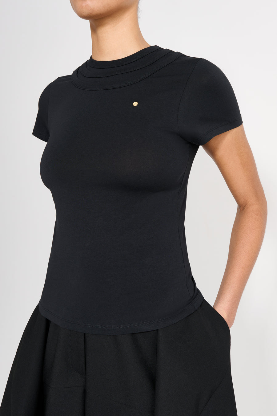 Black top worn by a person on a light gray background