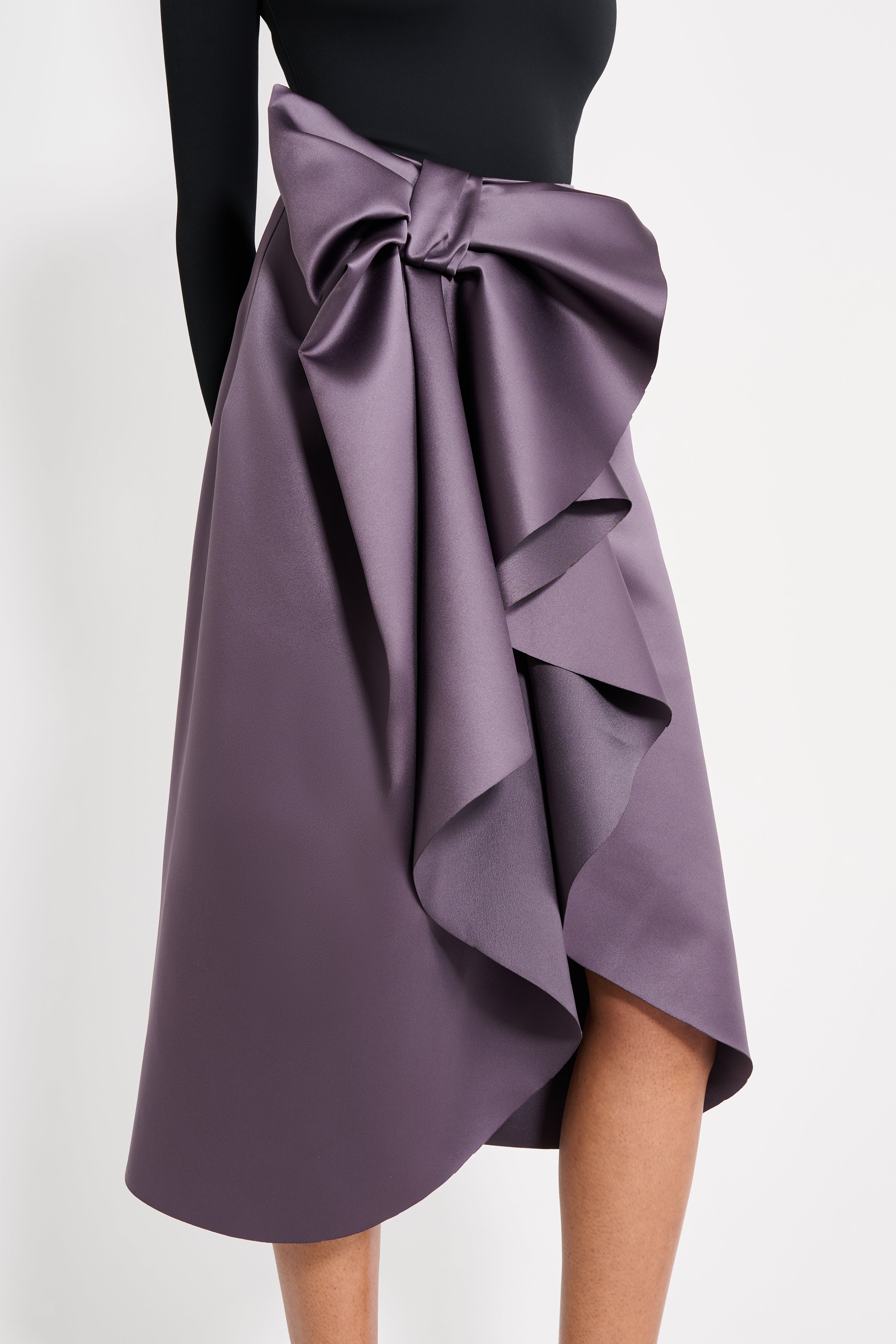 Model wearing a black body with purple midi skirt on a white background.