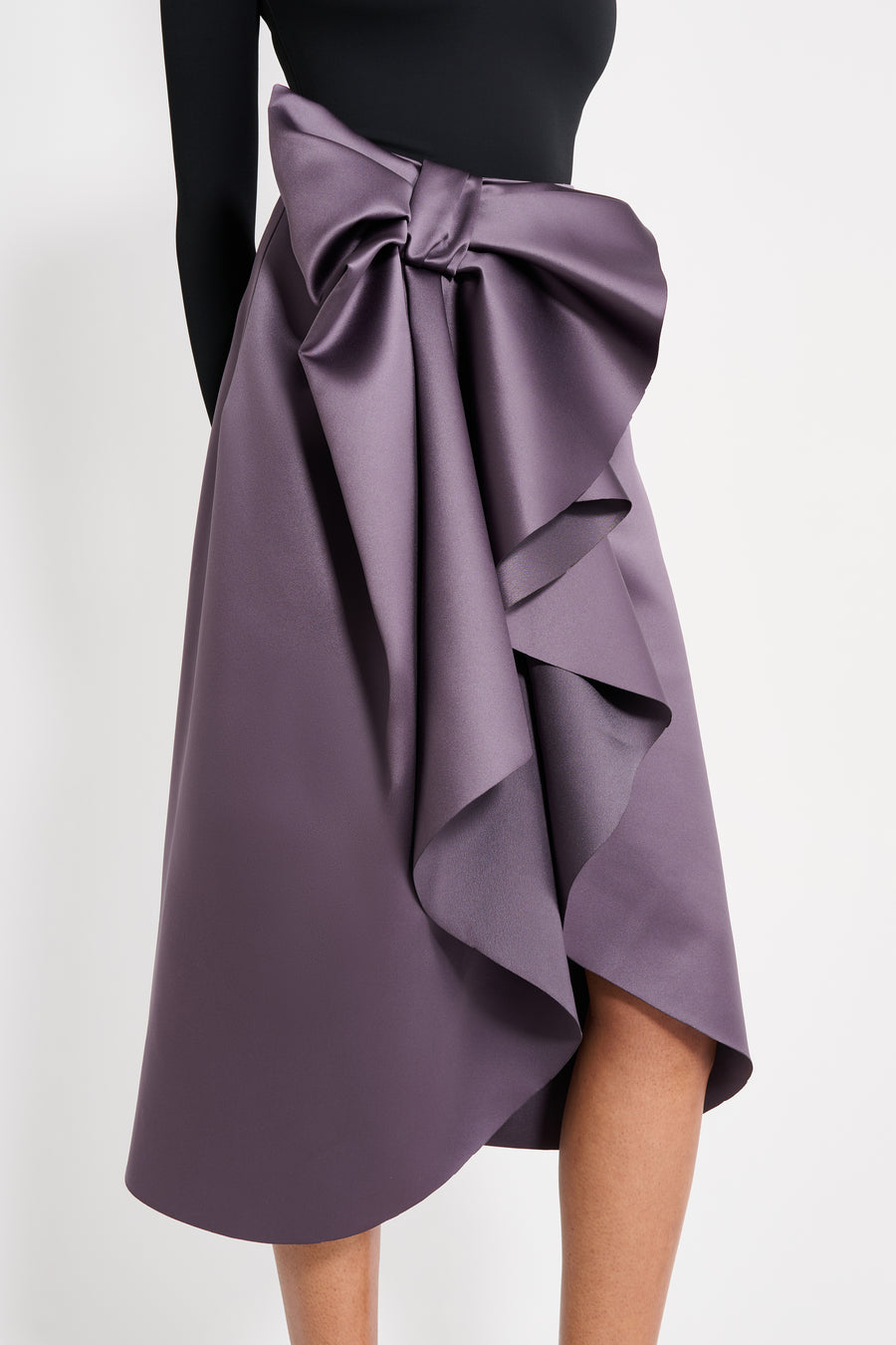 Model wearing a black body with purple midi skirt on a white background.