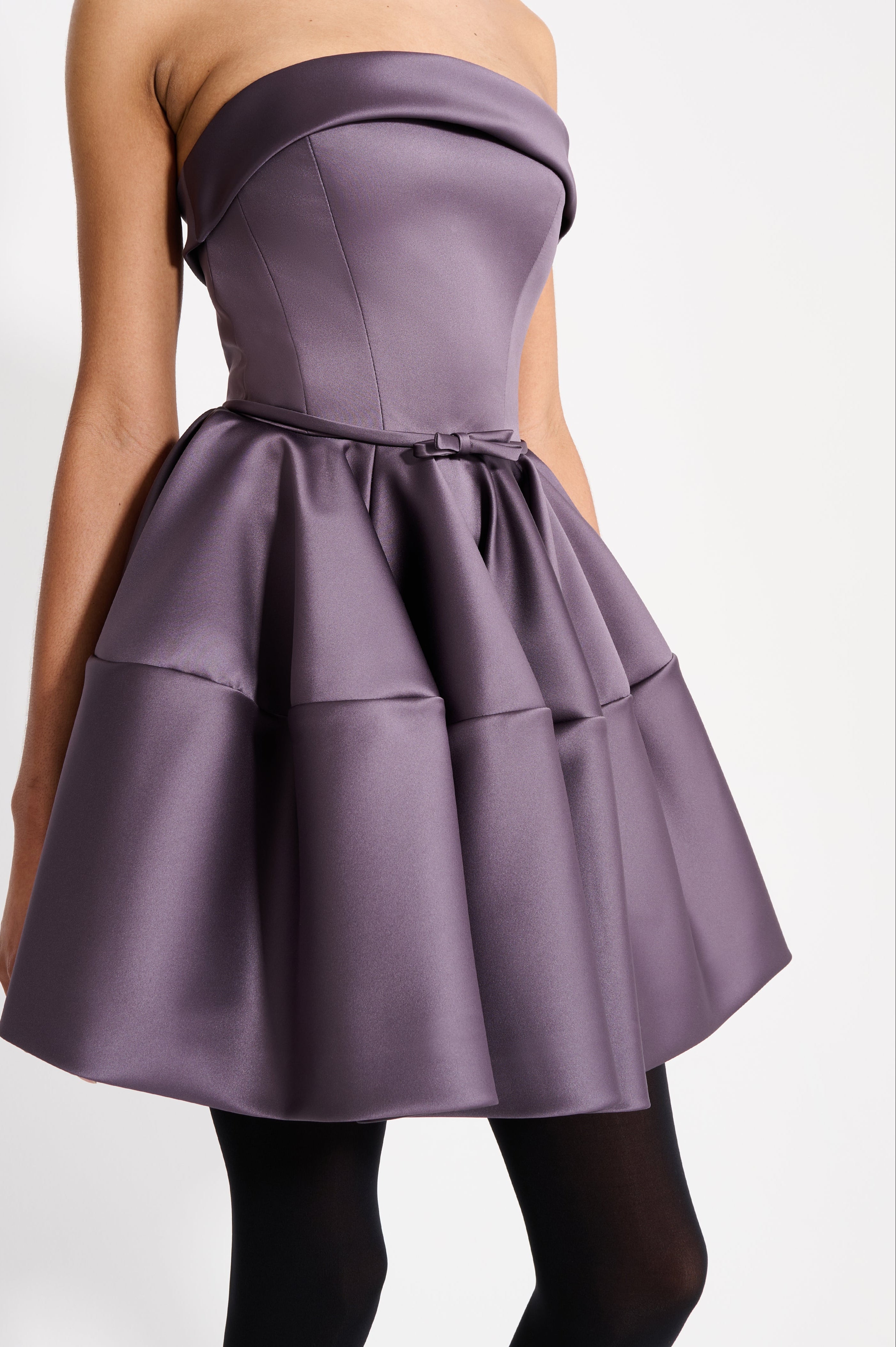 Model wearing a purple mini dress on a white background.