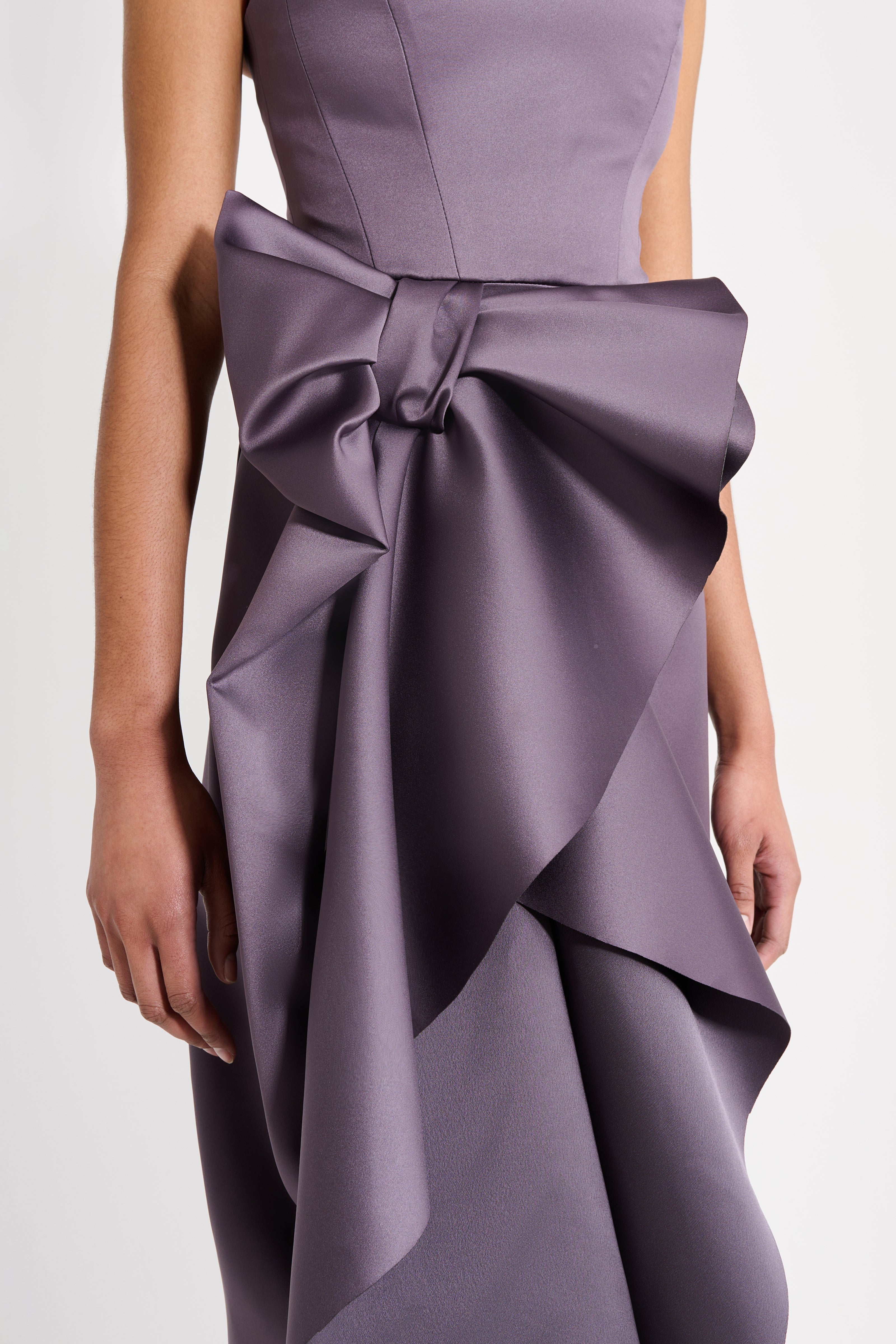 Model wearing a long purple dress on a white background.