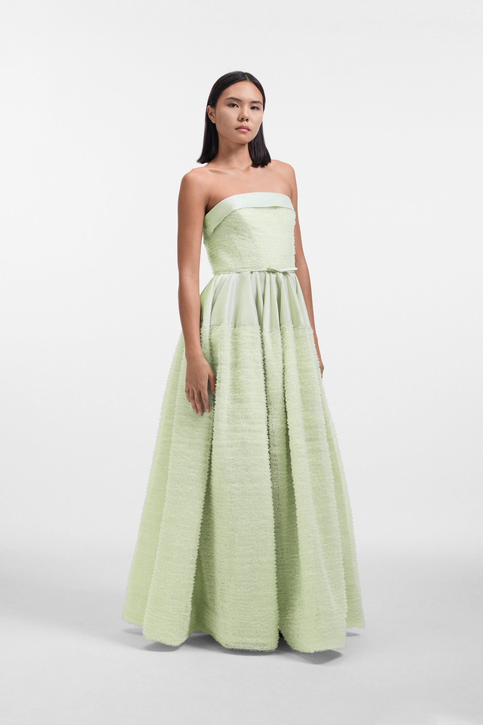 Model wearing a mint green strapless tulle gown on a white background.