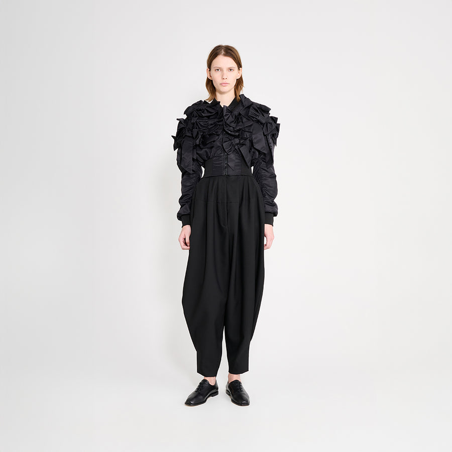 Model wearing black trousers with a bomber jacket on a white trousers.