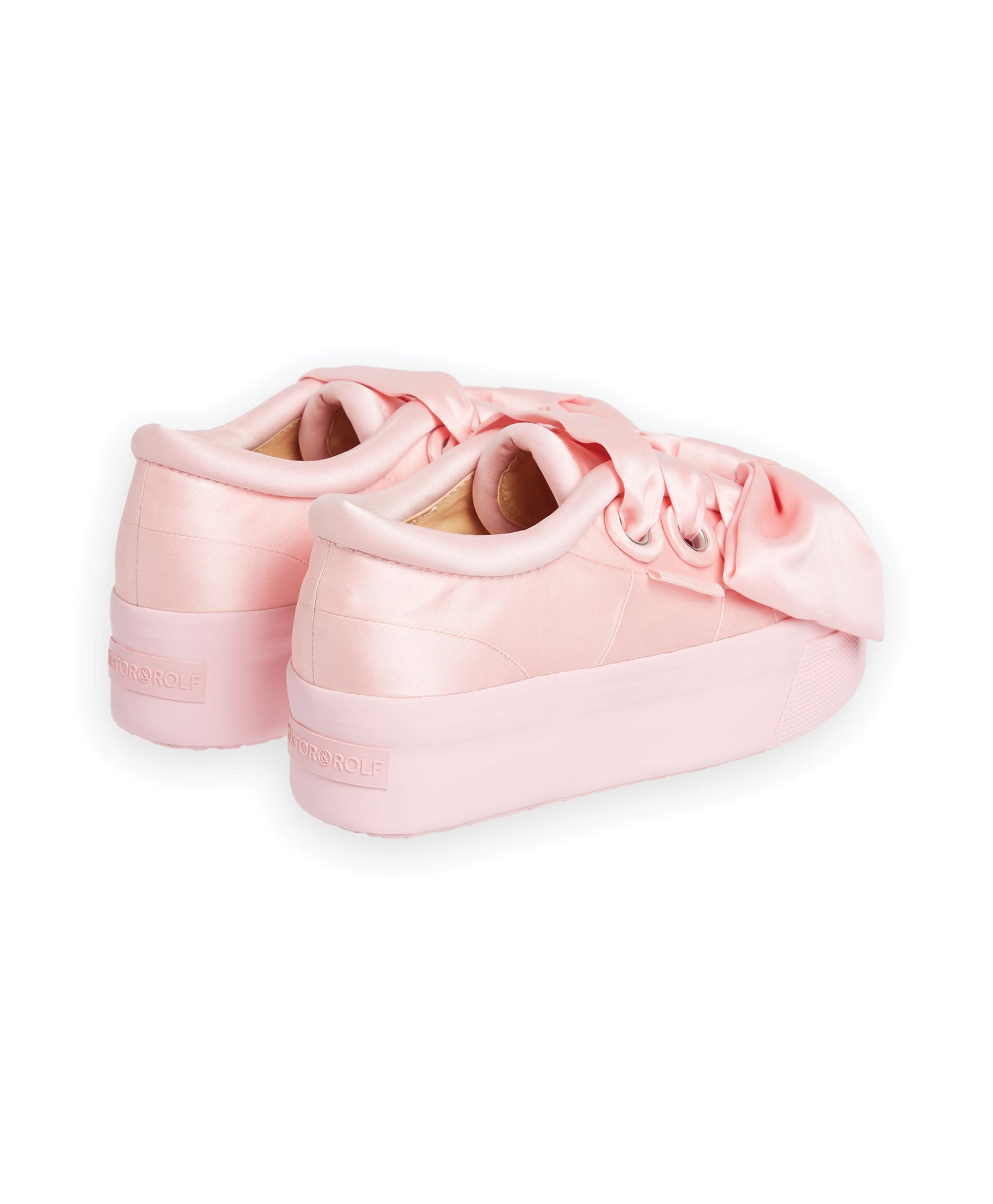 Pink satin platform sneakers with oversized bow detailing, featuring subtle stitching and tonal brand embossing on the heel.