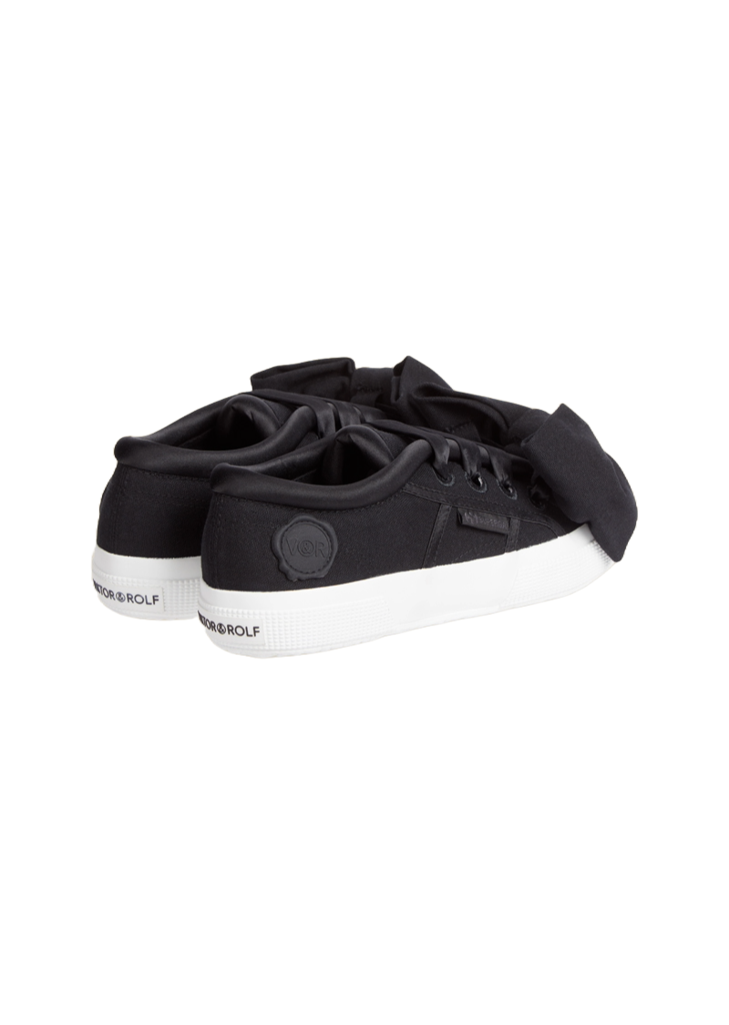 Black satin sneakers with oversized bows and white rubber soles featuring an embossed logo at the back.