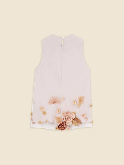 Sleeveless blush pink blouse with decorative floral appliqués and button closure on a soft beige background.