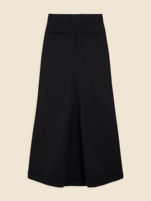 Wide-leg black culottes with a tailored fit, featuring neat pleats and subtle cuffed hems, crafted from smooth wool fabric.