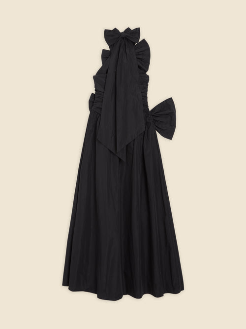 Elegant black evening gown with ruffled bodice, oversized bows, and floor-length skirt on a neutral background.