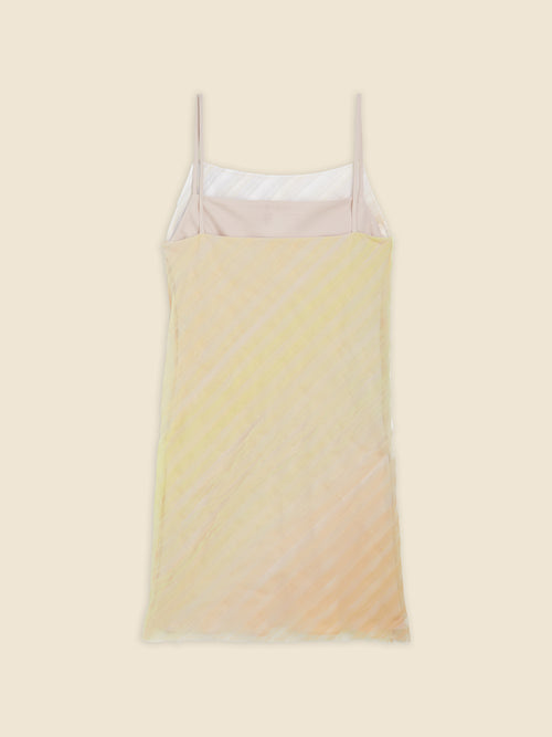 Pastel yellow and peach sheer slip dress with spaghetti straps displayed on a light beige background.