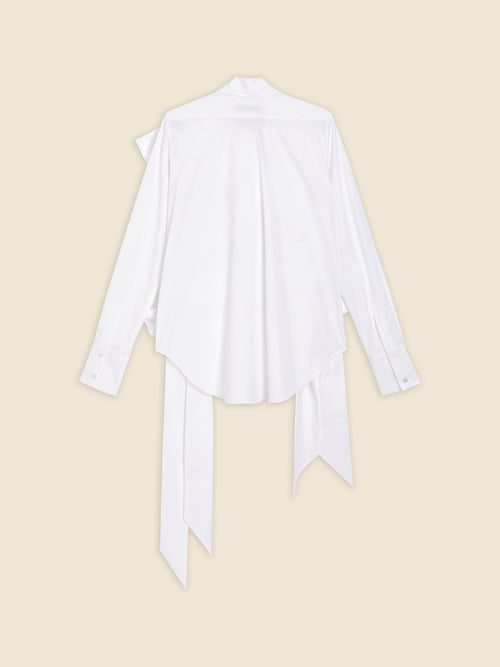 Back view of a white satin blouse with long flowing ties, buttoned cuffs, and a loose fit on a soft beige background.