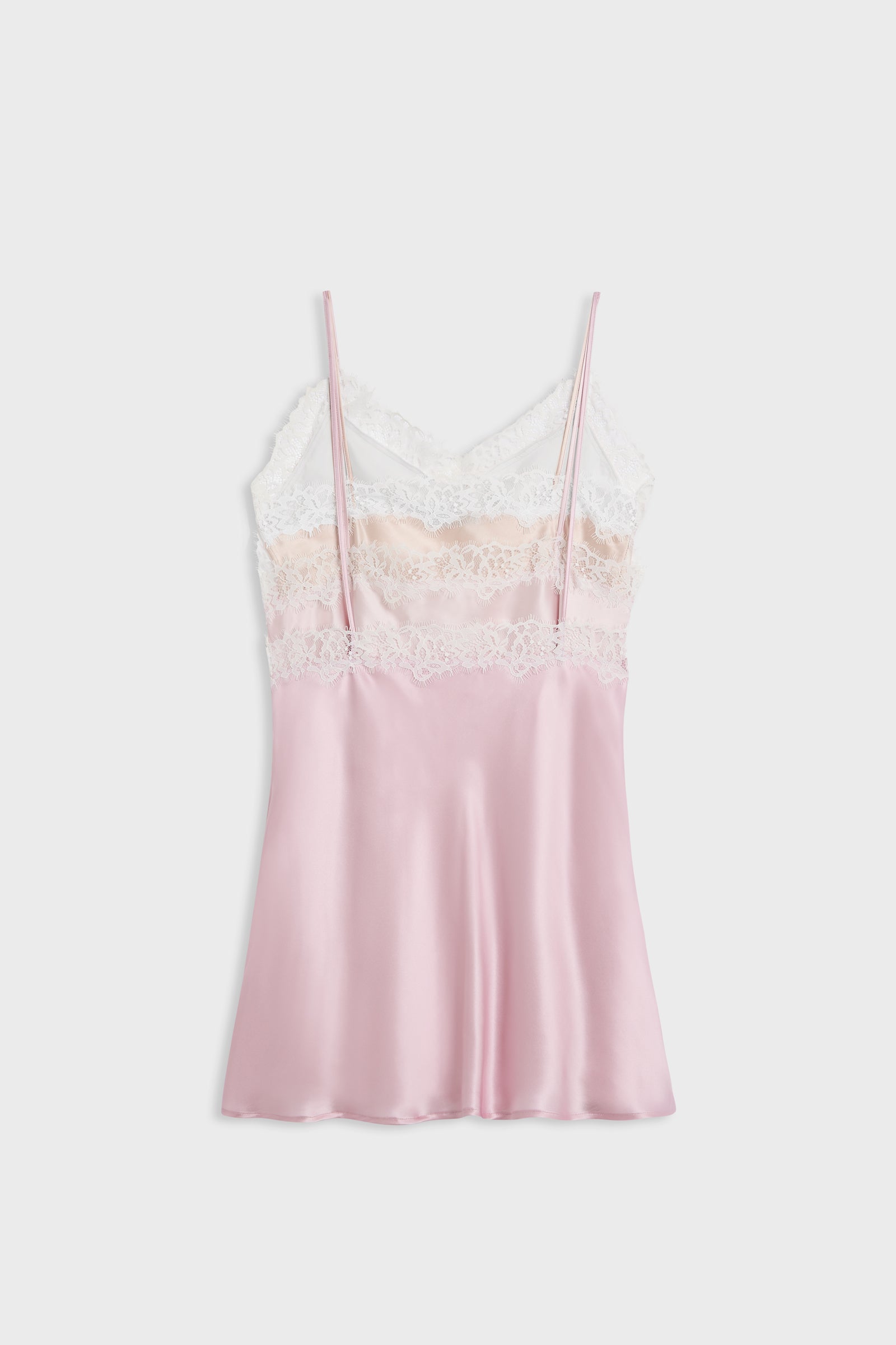 A light pink satin slip dress with thin straps, a white lace bodice, and a beige lace band, displayed against a light gray background.