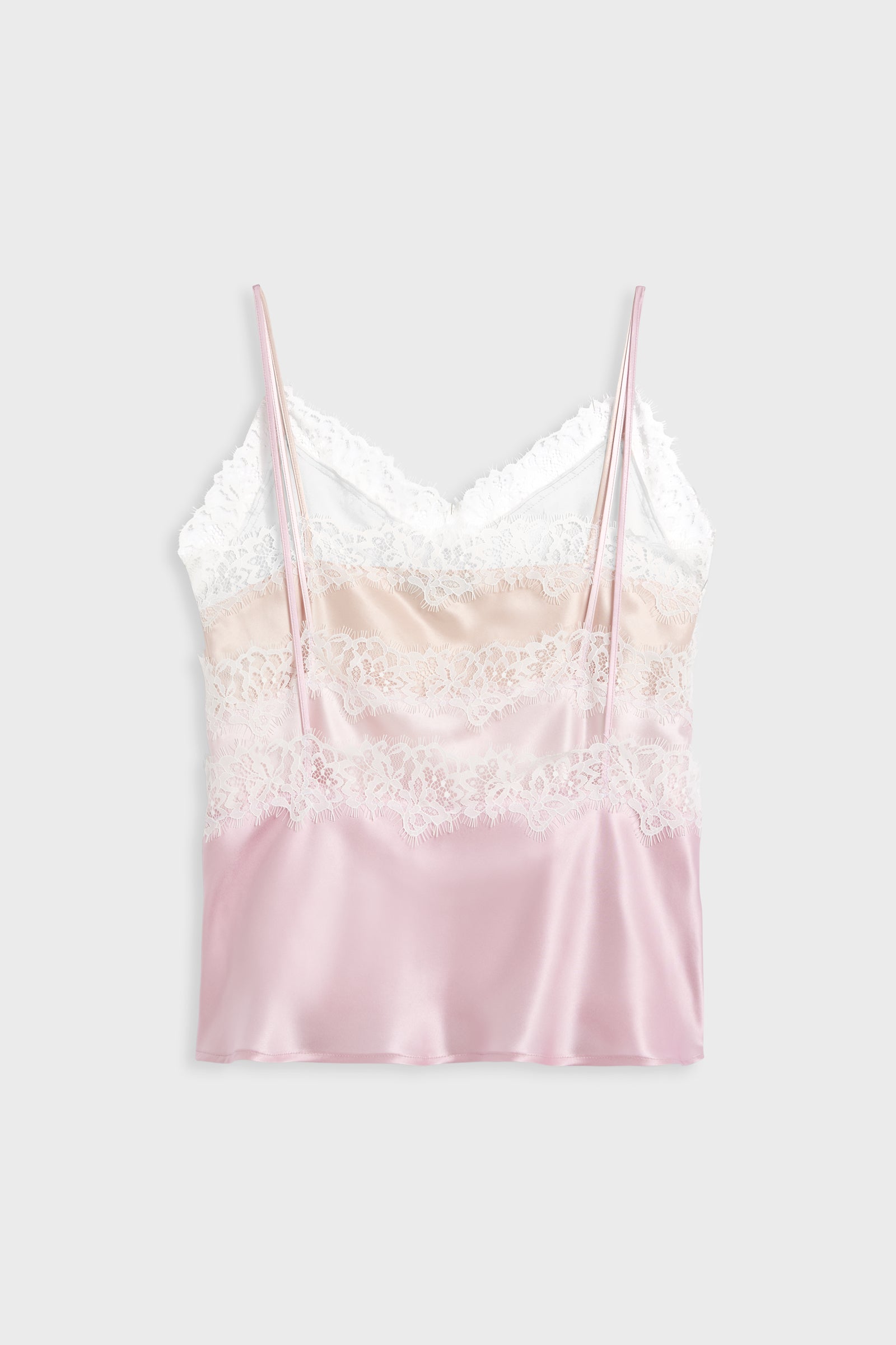 A satin camisole top with a color-blocked design in white, pale pink, and light peach, featuring white lace trim and thin spaghetti straps, shown against a light gray background.