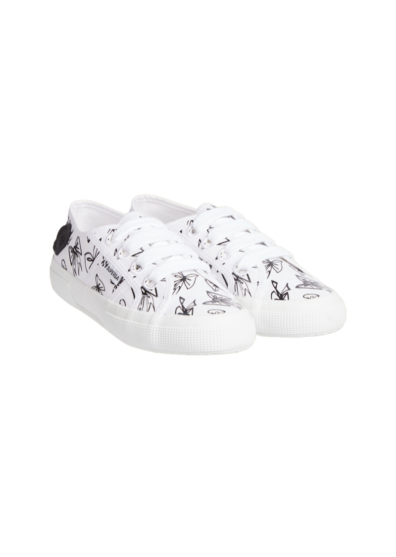 White canvas sneakers feature intricate black bow illustrations, enhanced by textured rubber soles and classic lace-up design.