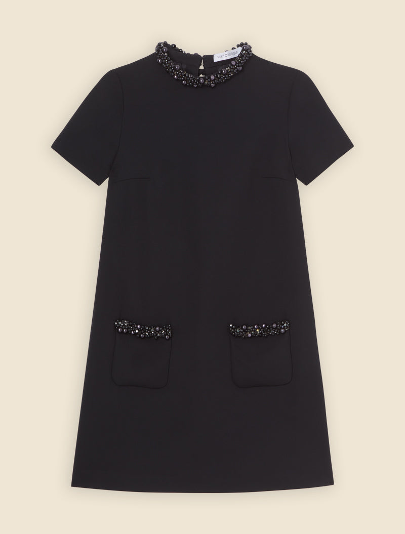 A-line black dress with short sleeves featuring intricate pearl embellishments on the collar and pocket edges.