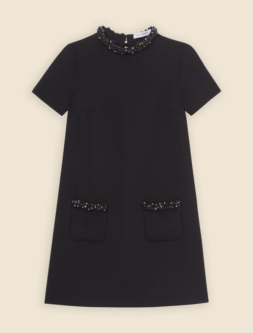 A-line black dress with short sleeves featuring intricate pearl embellishments on the collar and pocket edges.