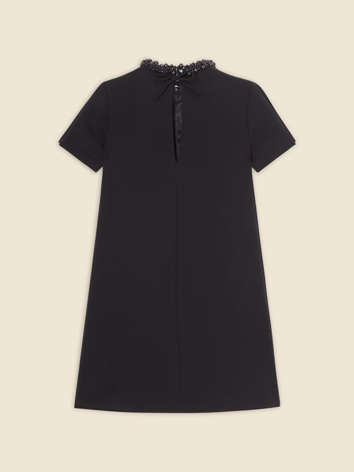 Black A-line dress with short sleeves and a round neckline, adorned with intricate black bead embellishments around the collar.